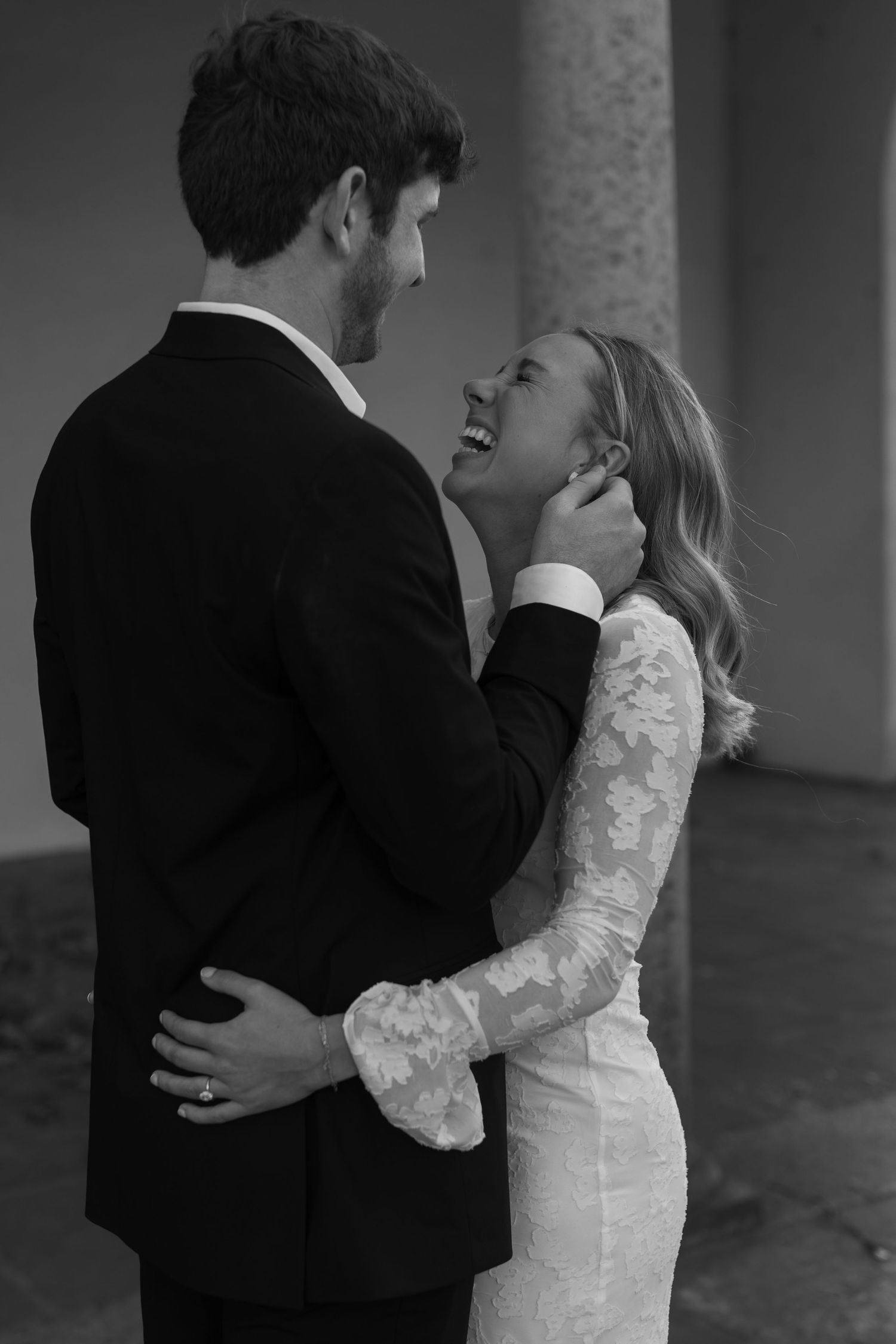 An intimate black and white portrait of a couple sharing a tender moment in formal attire.