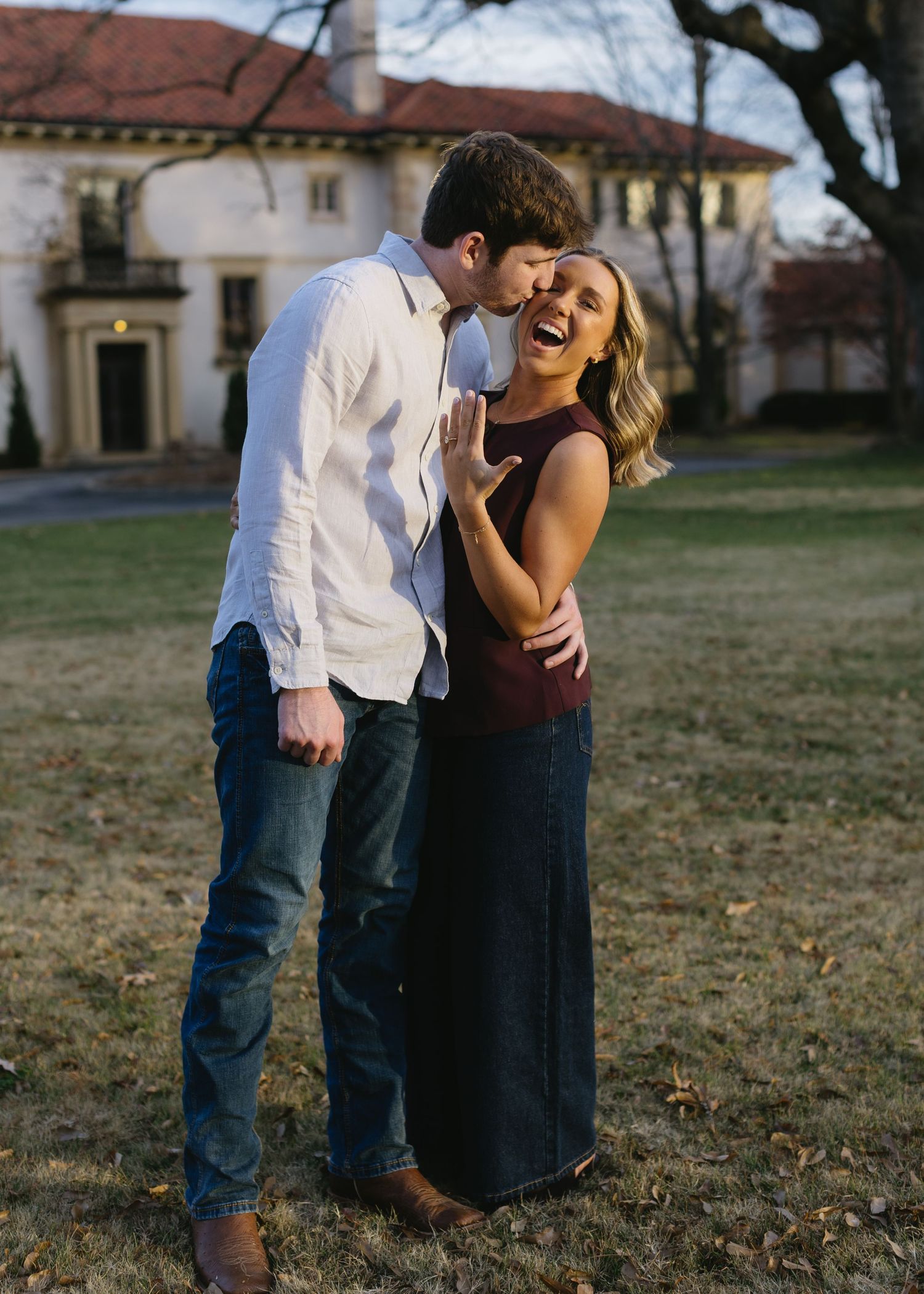 A couple shares affectionate moments during a sunset photoshoot with historic buildings in the background.