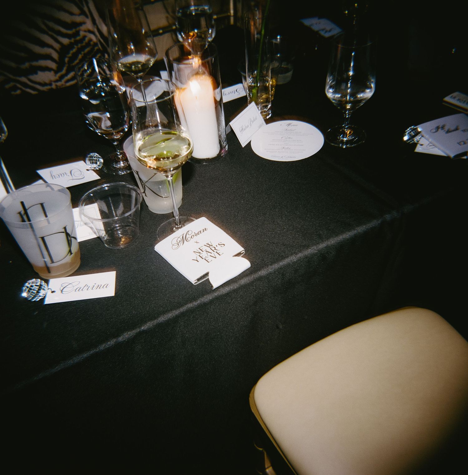 Dark interior table setting at a restaurant with wine glasses and place settings arranged in a row.