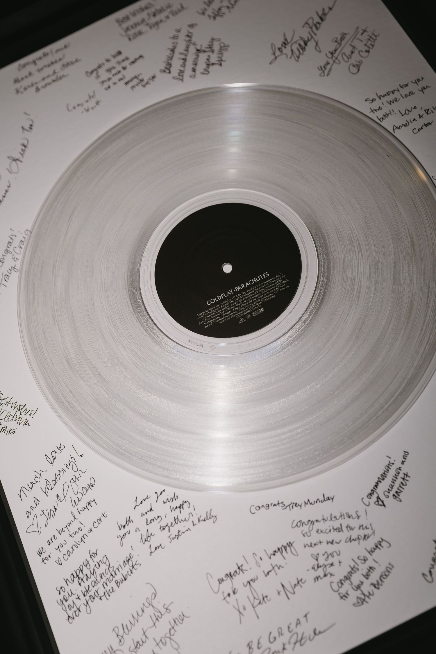 Clear vinyl record with handwritten messages and signatures around the edges.