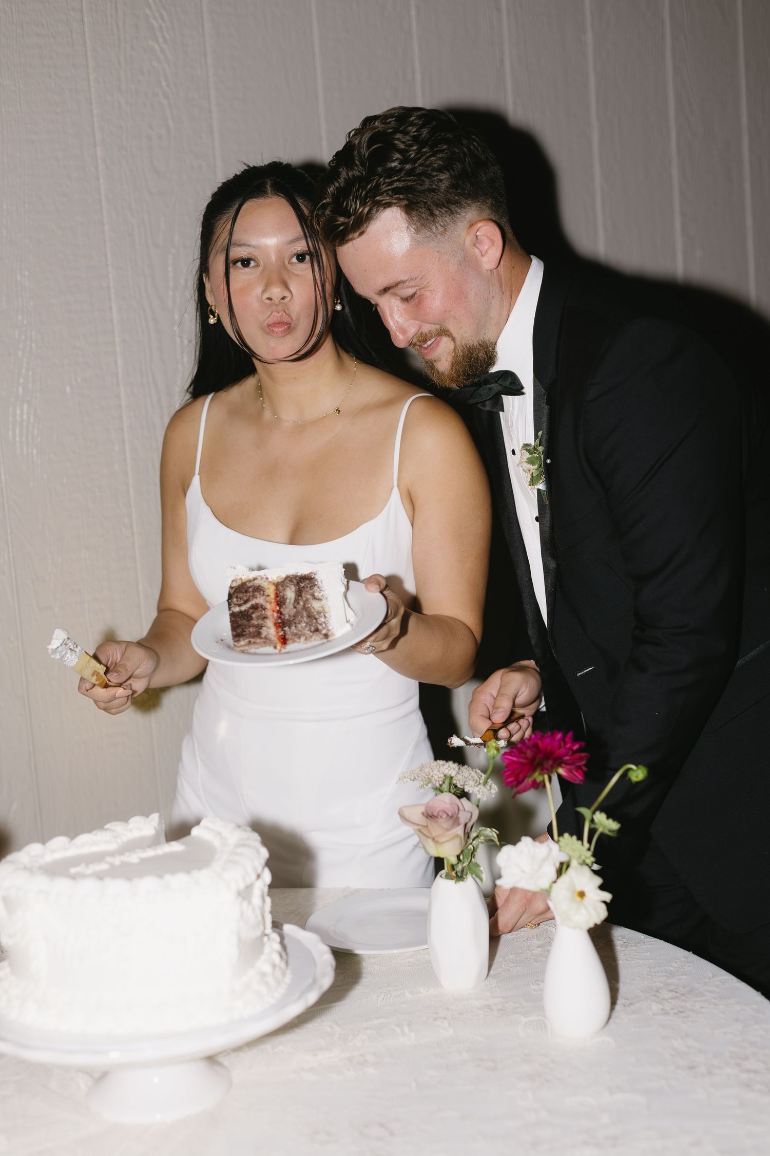 Couple cuts their white wedding cake together at reception.