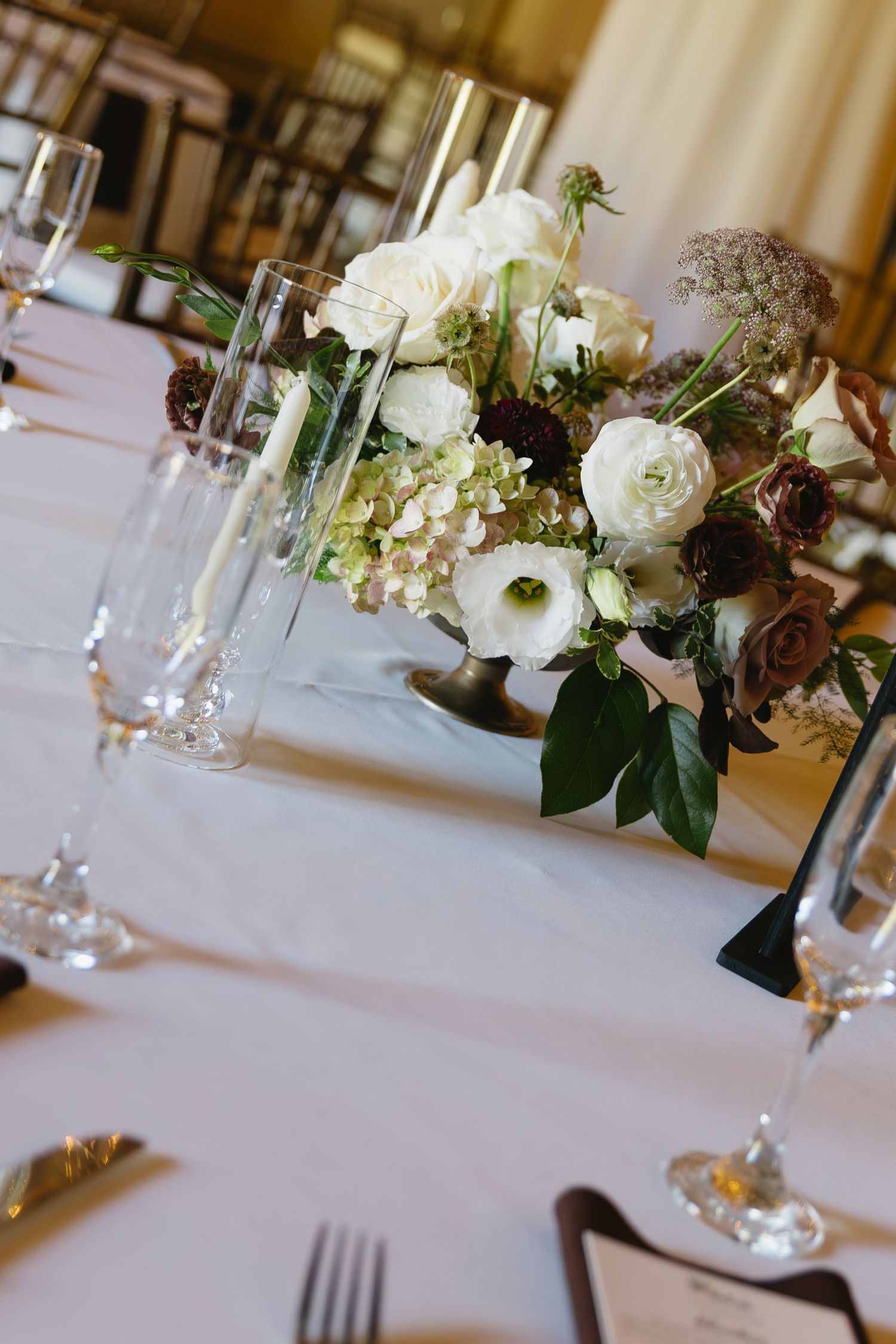 Elegant wedding table settings with white floral centerpieces and crystal glassware on crisp white linens.