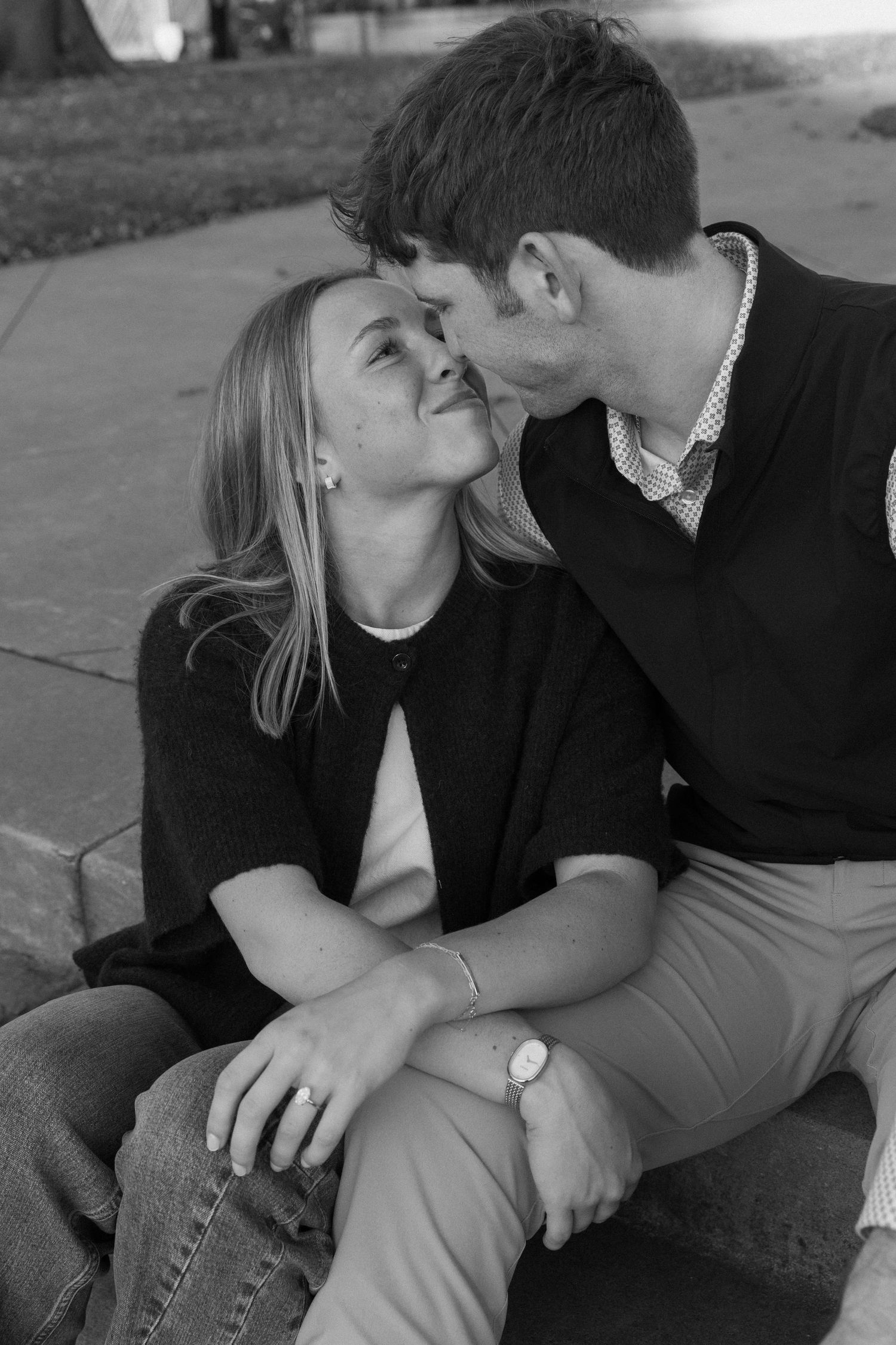 Intimate black and white photo of a couple sharing a romantic moment outdoors.