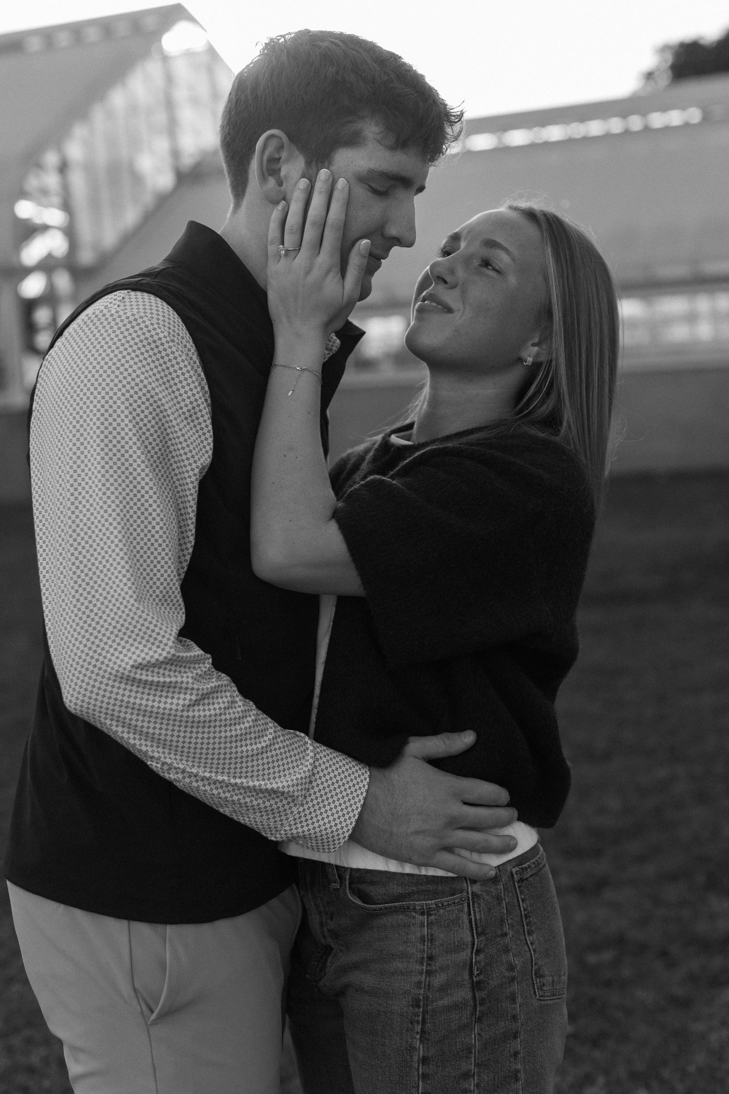 Two people share an intimate moment outdoors, one in a black top and the other in gingham pattern.