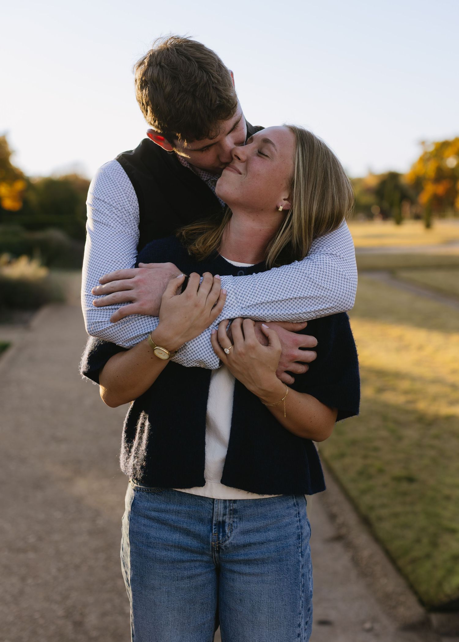 A couple shares intimate embraces and laughter during an outdoor golden hour photoshoot.
