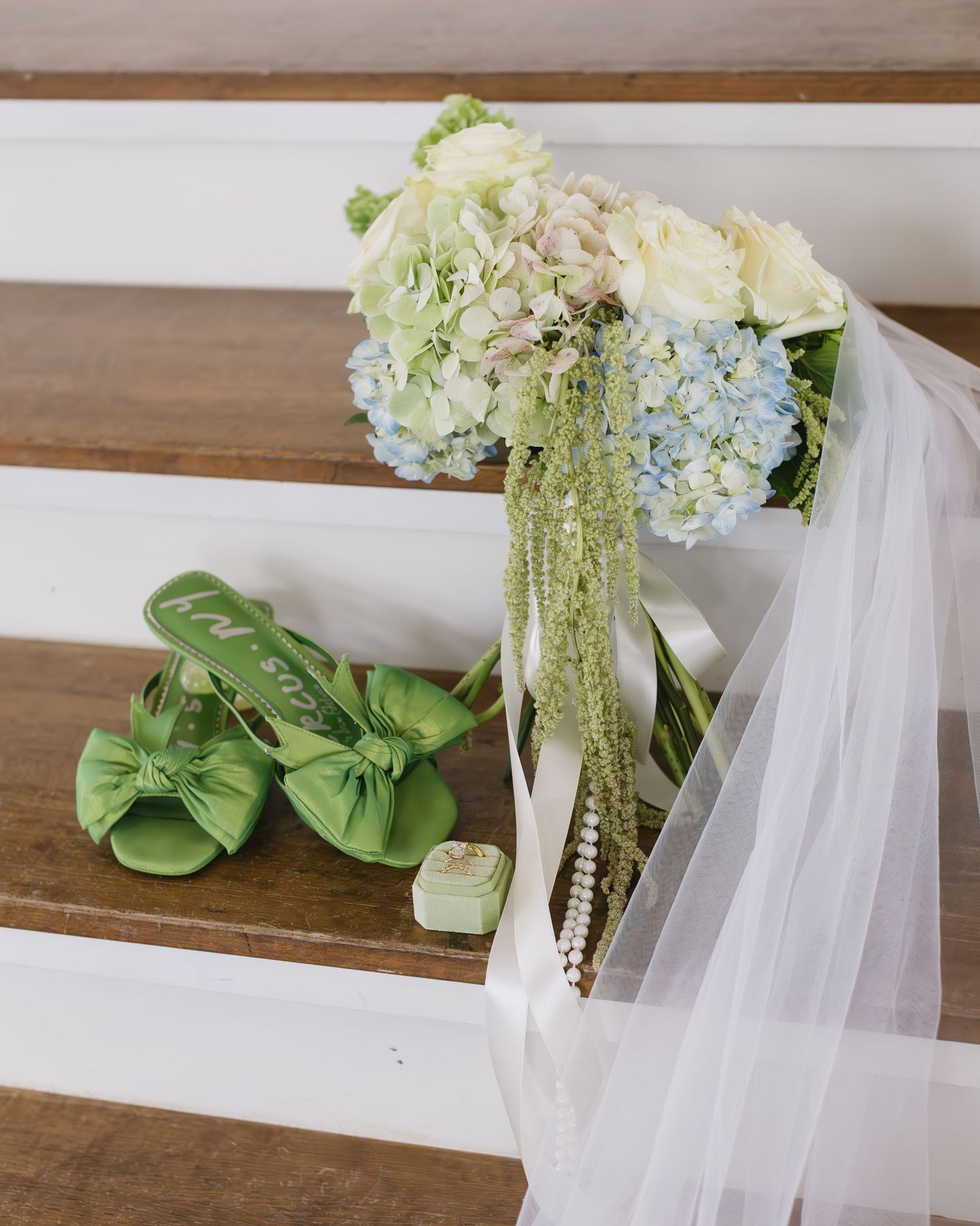 Sage green satin bow decorations and white tulle fabric arranged on a wooden surface for wedding decor.