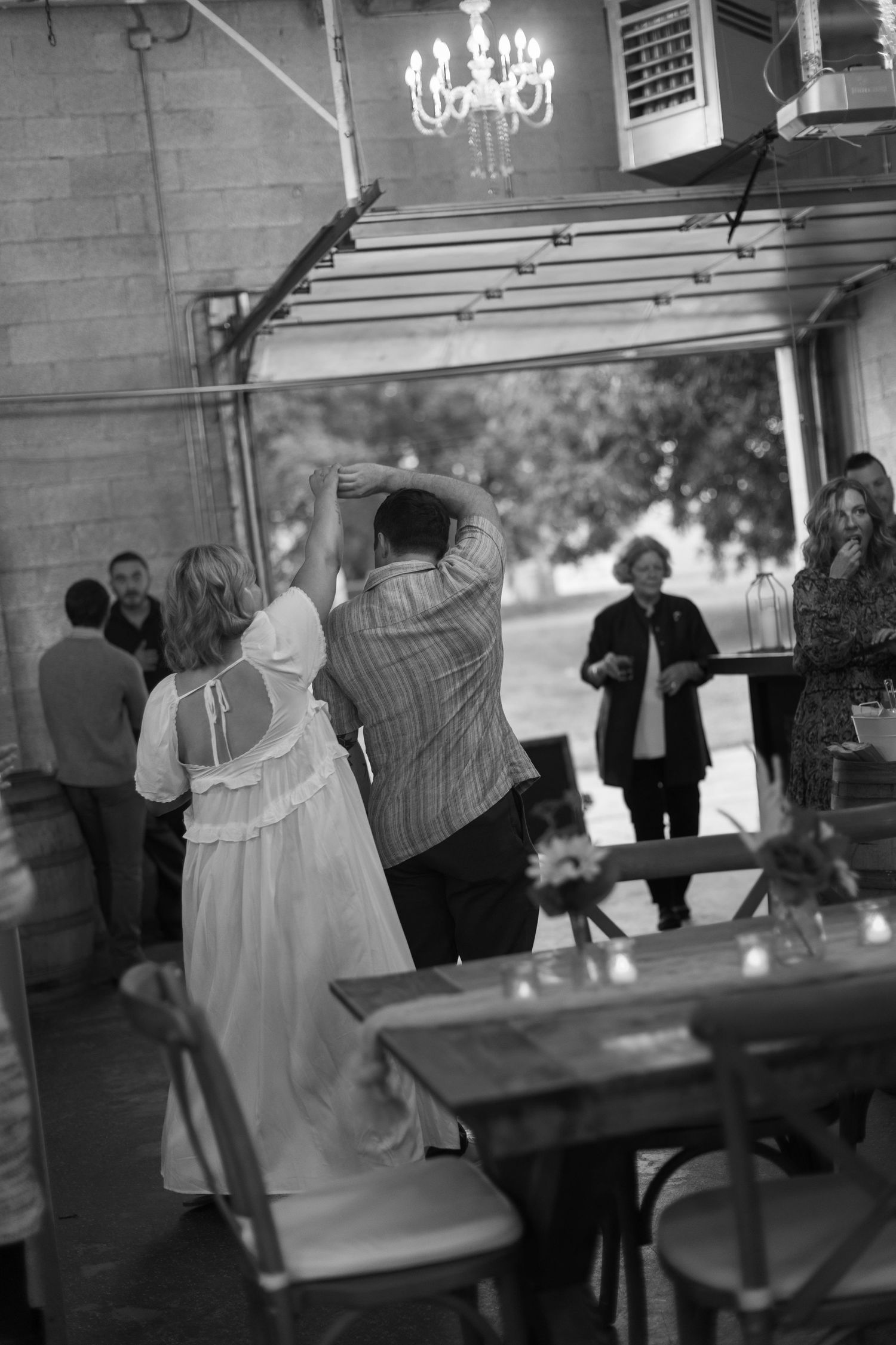 Couples dancing together in a dimly lit venue with chandeliers overhead.