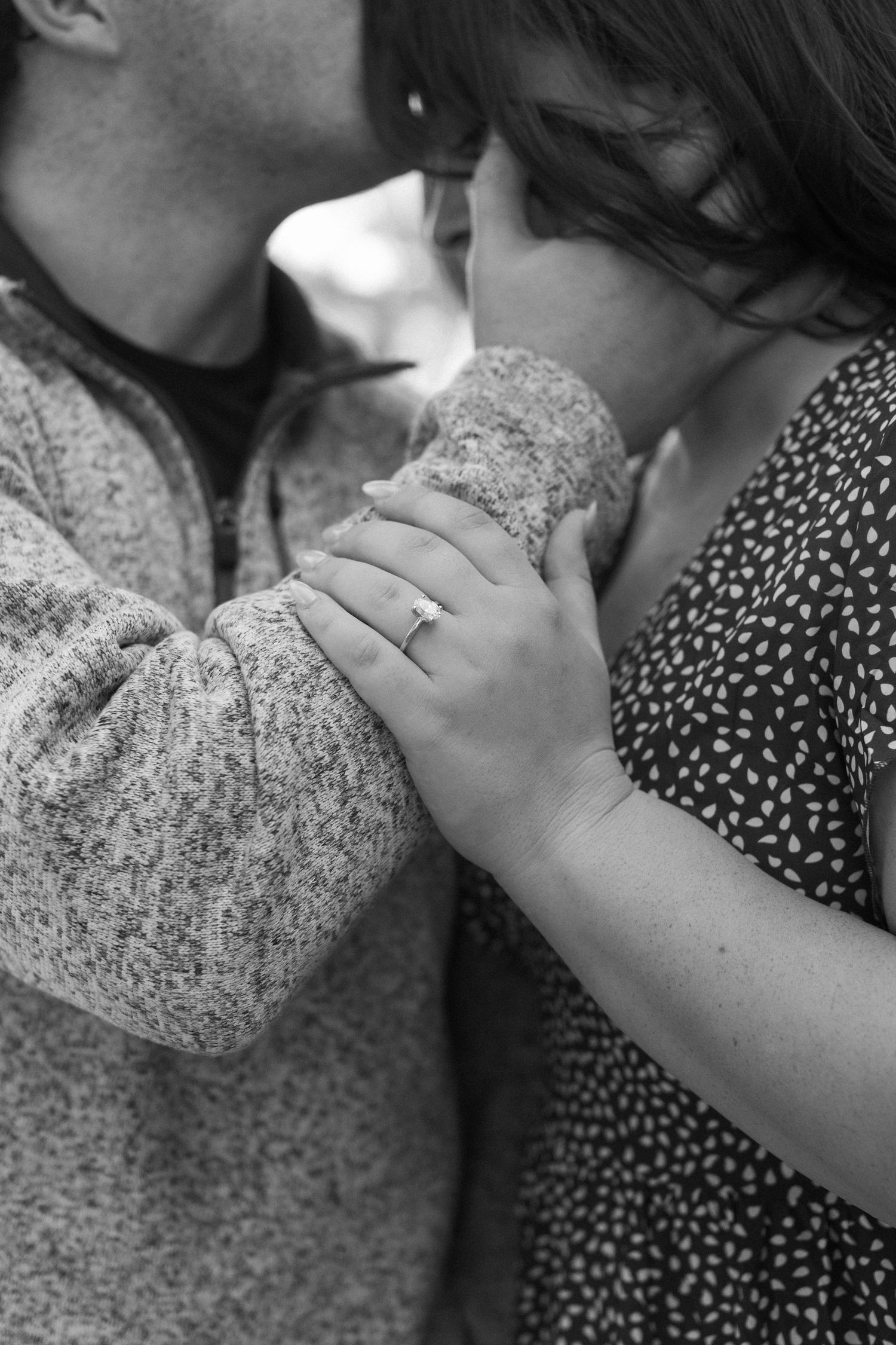 A black and white close-up of hands and a ring during an intimate moment.