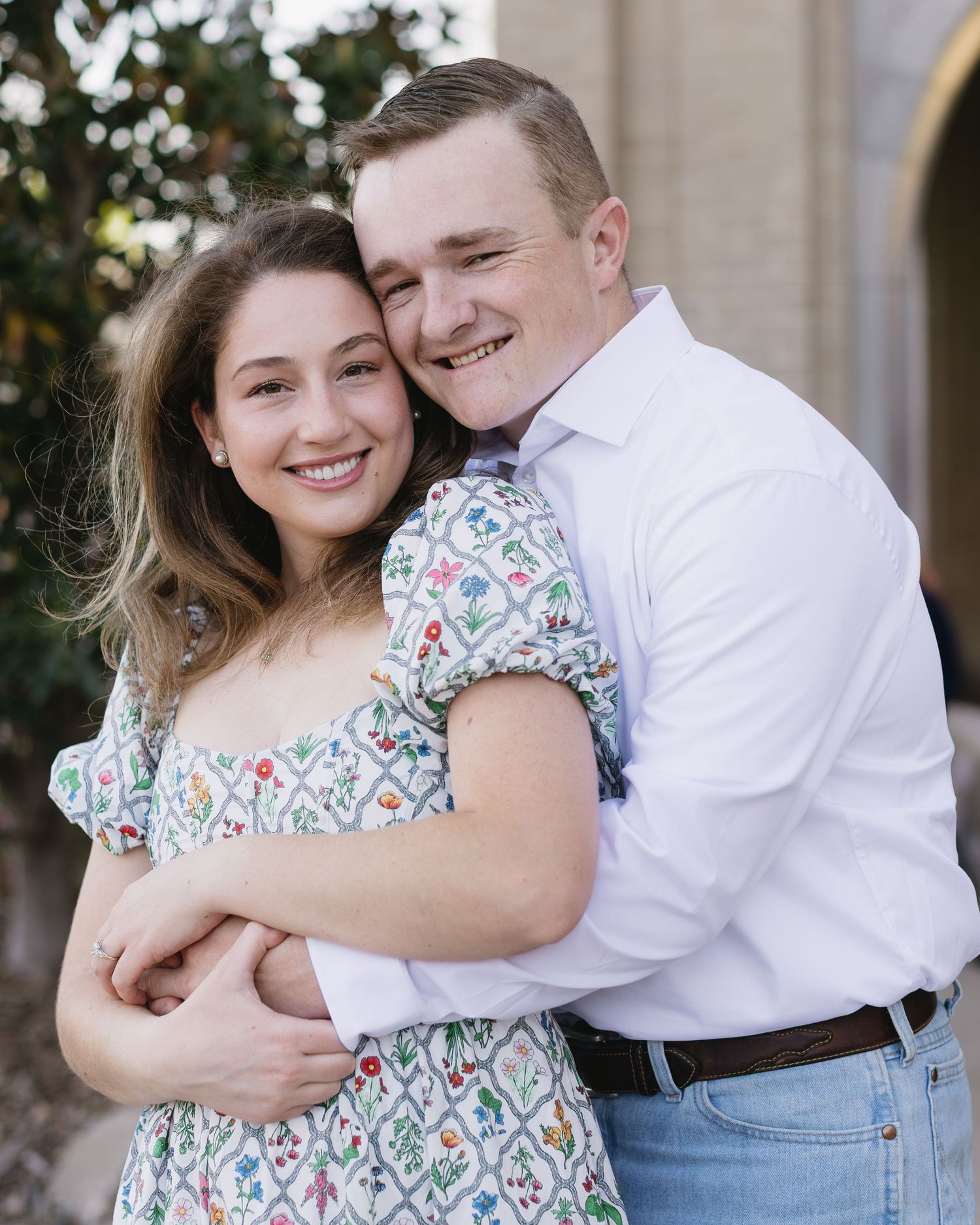 A happy couple shares an intimate moment together against a stone building backdrop.