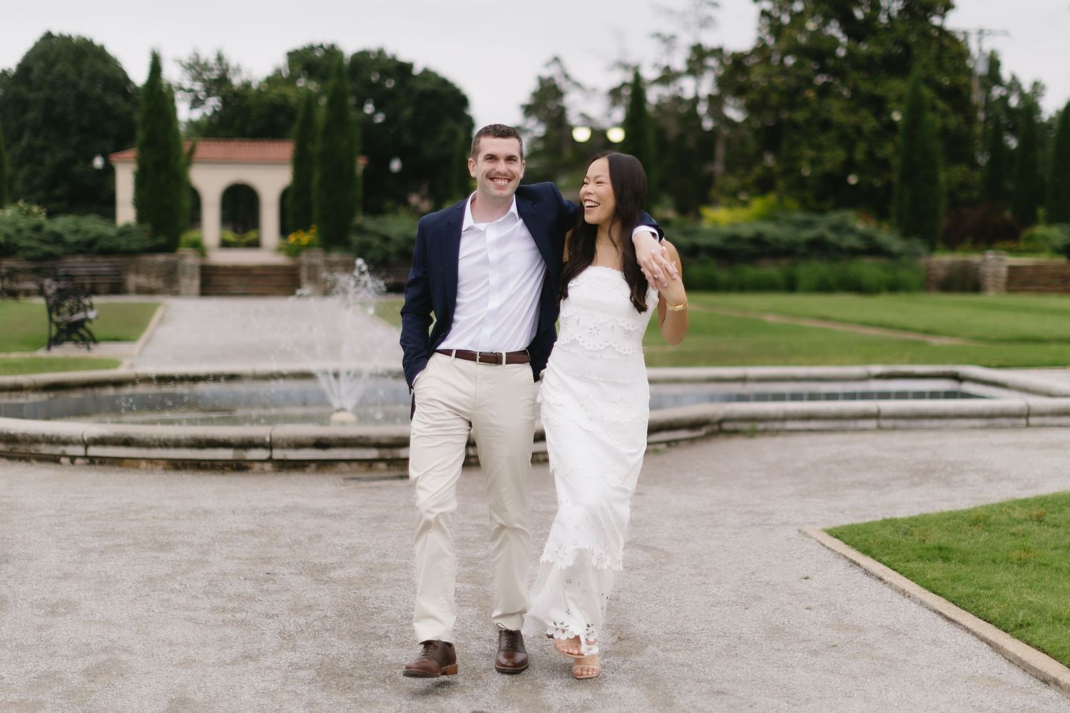 A romantic engagement shoot in an elegant garden setting with brick pathways and greenery.