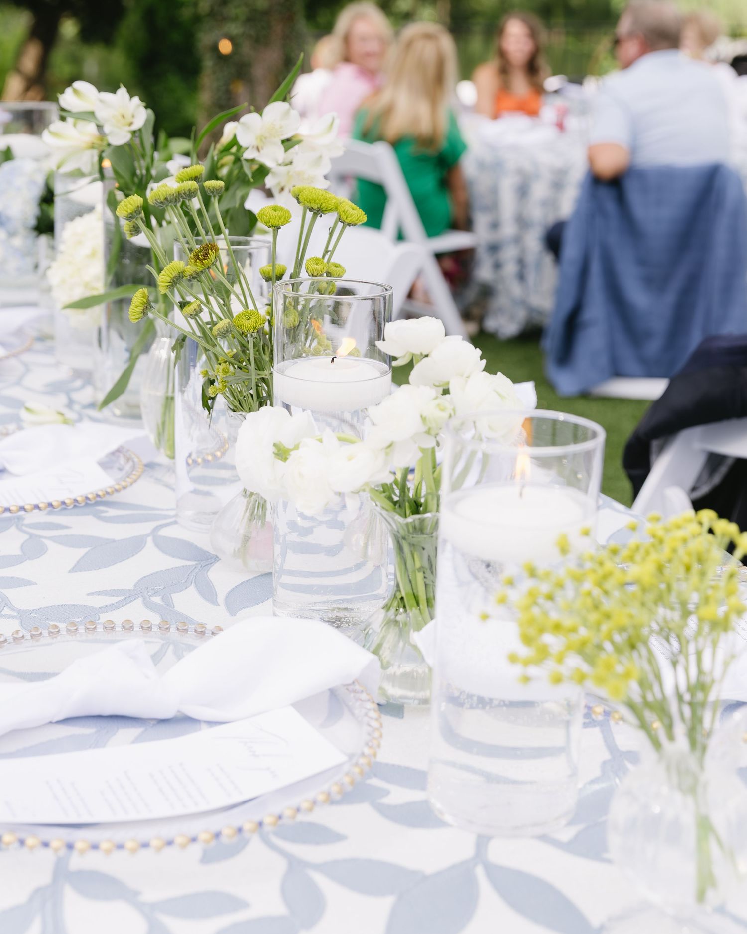 Outdoor wedding reception tables with white flowers, glassware, and light blue table settings.
