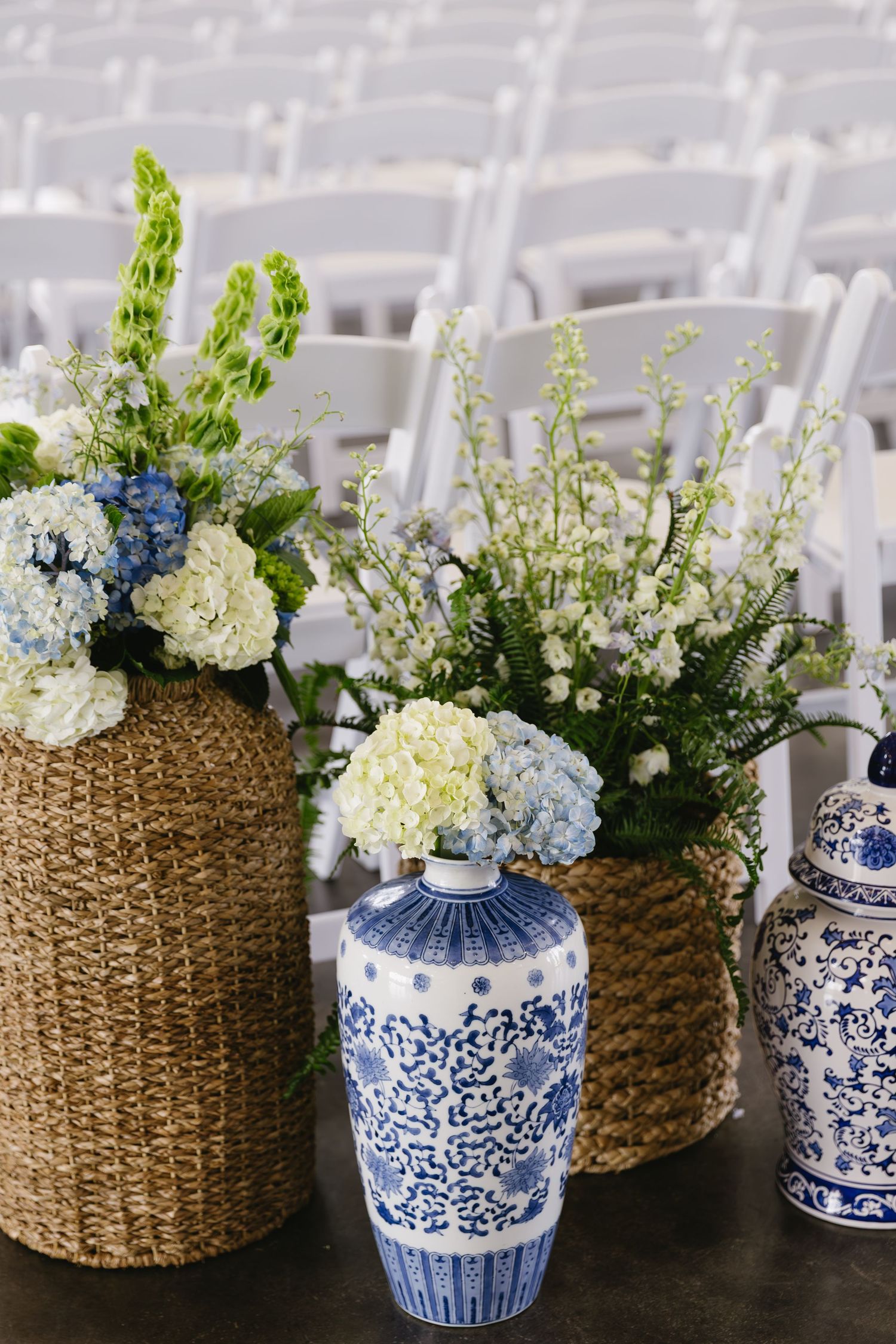 Blue and white porcelain vases paired with woven baskets holding floral arrangements.