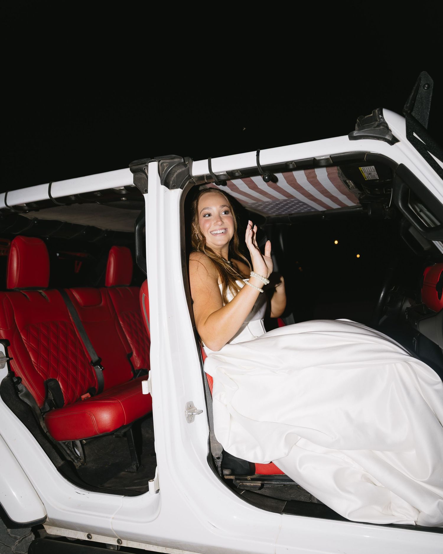 Wedding couple getting into car with red interior seats after ceremony.