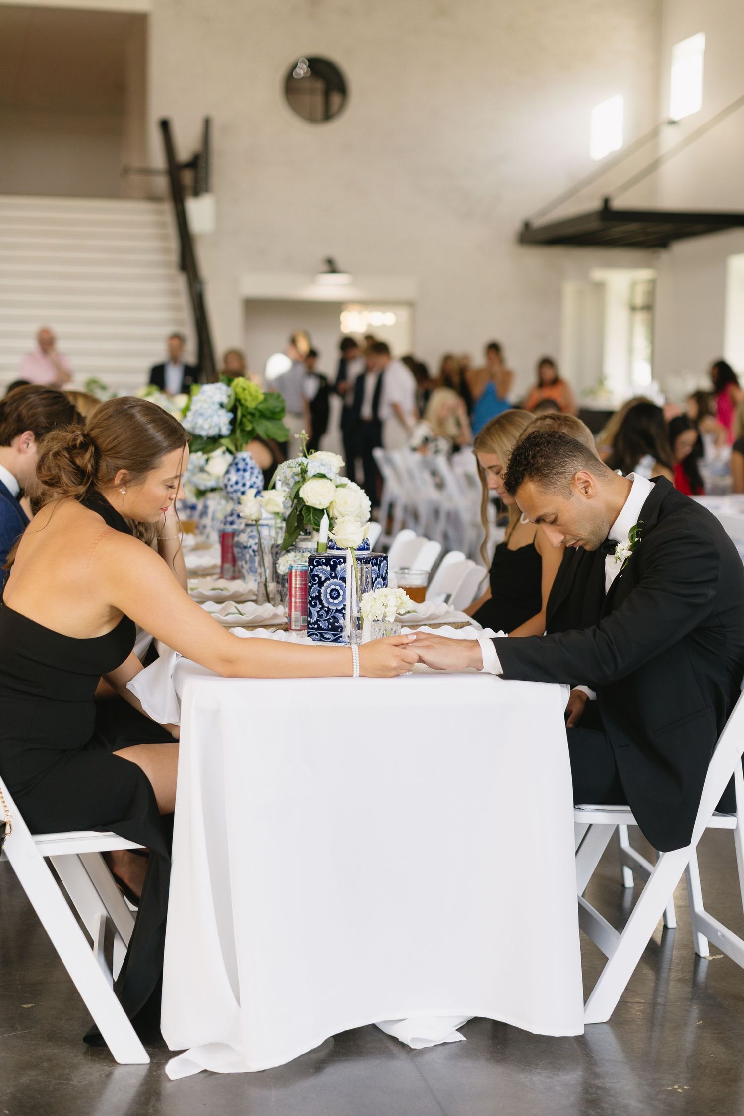 Wedding reception hall set with white linens and decorated tables for guests.