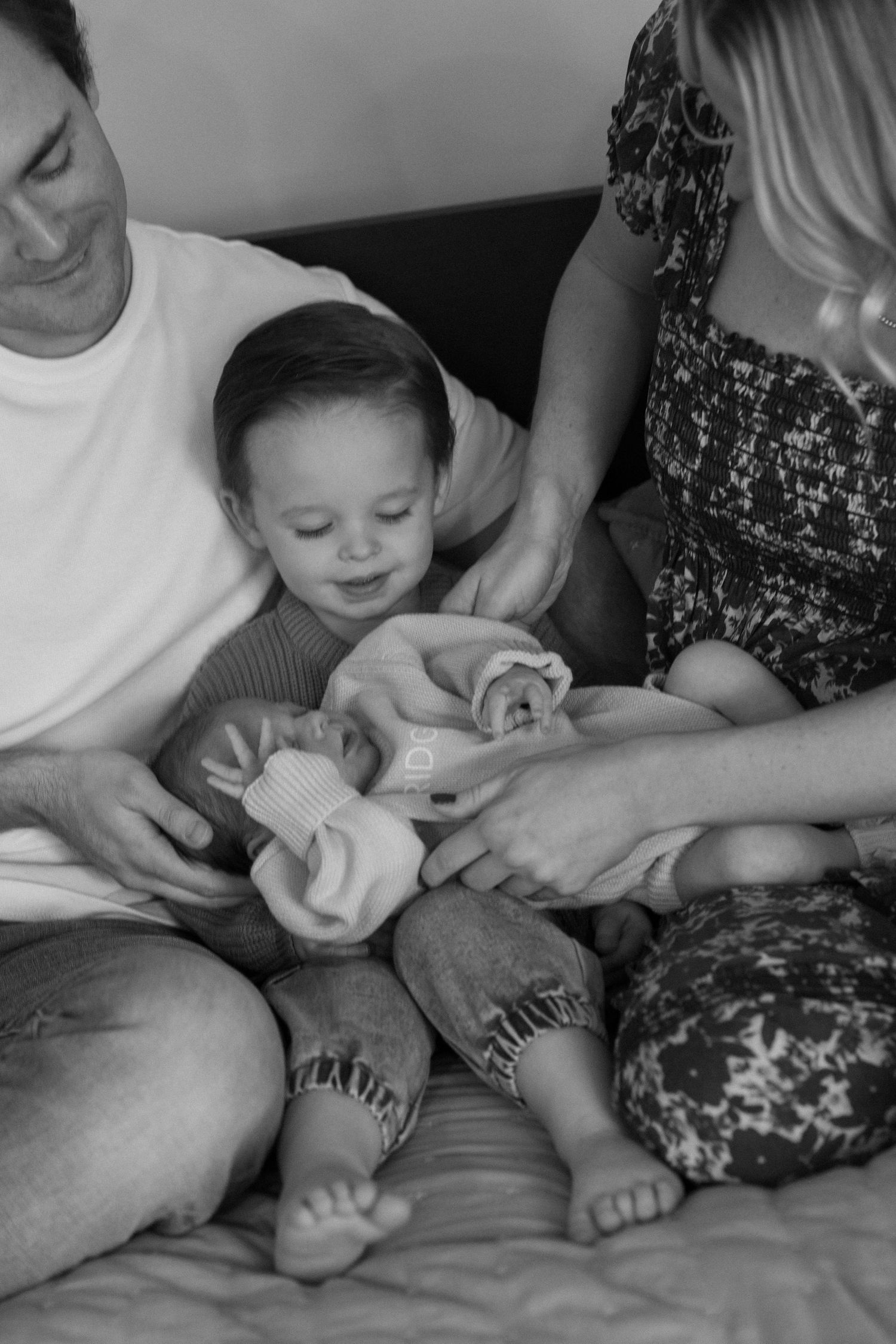Close-up black and white photos showing tender moments between parents and baby on a couch.