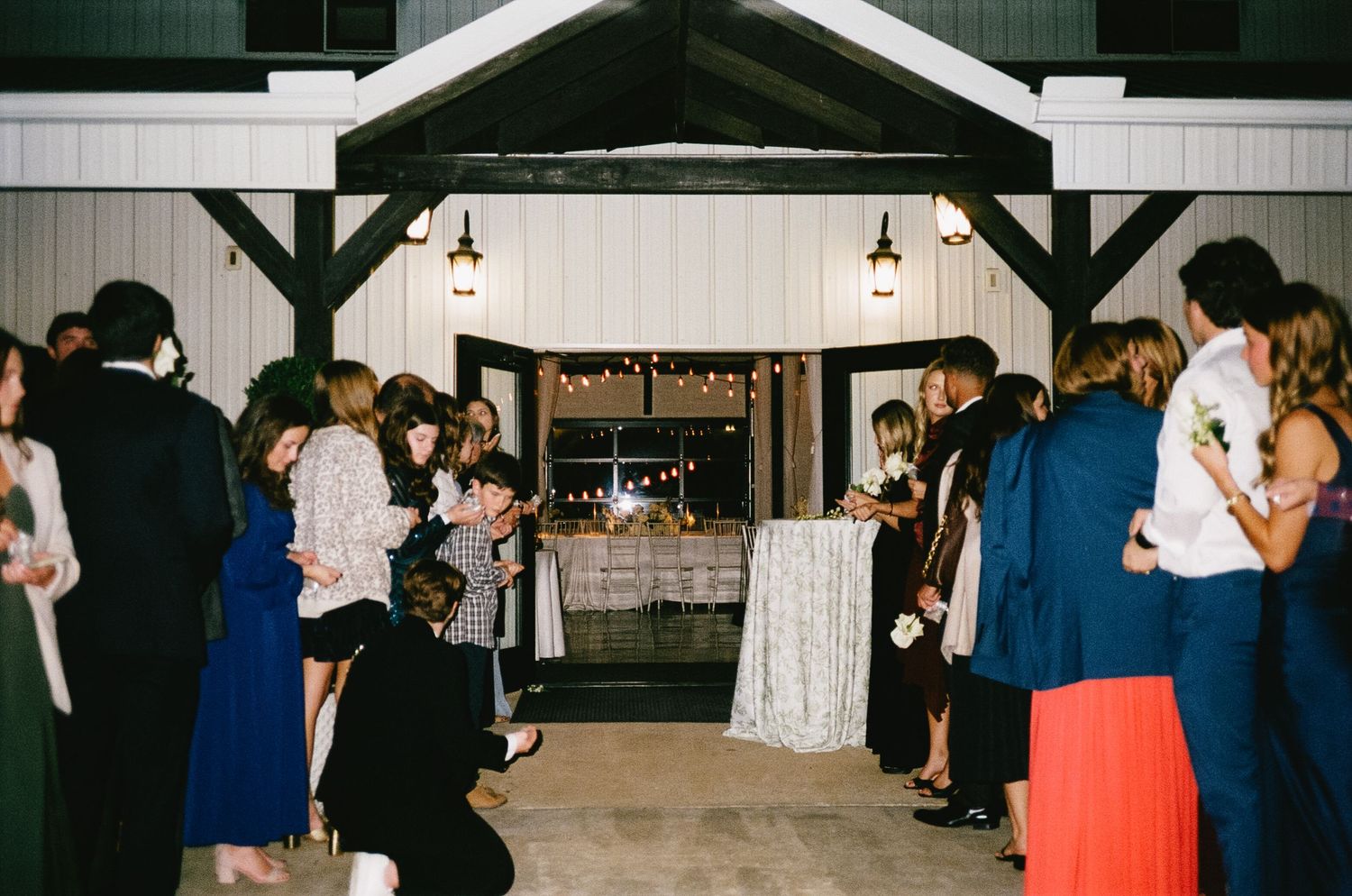 Wedding guests dancing in formal attire at an indoor reception venue.