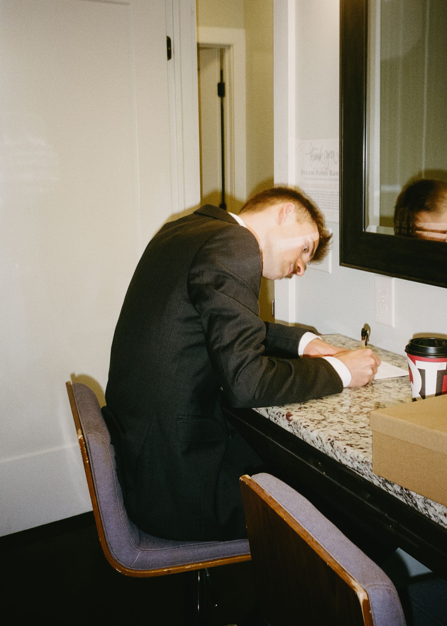 Person in formal attire writing at a desk during a wedding event.