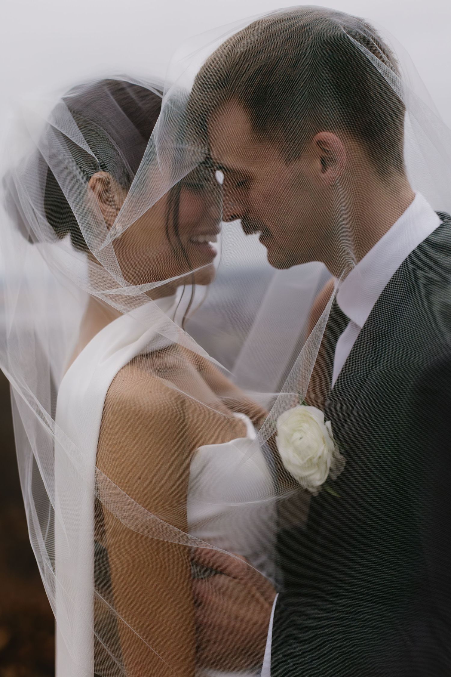 Romantic wedding moment captured in soft focus with white veil detail.