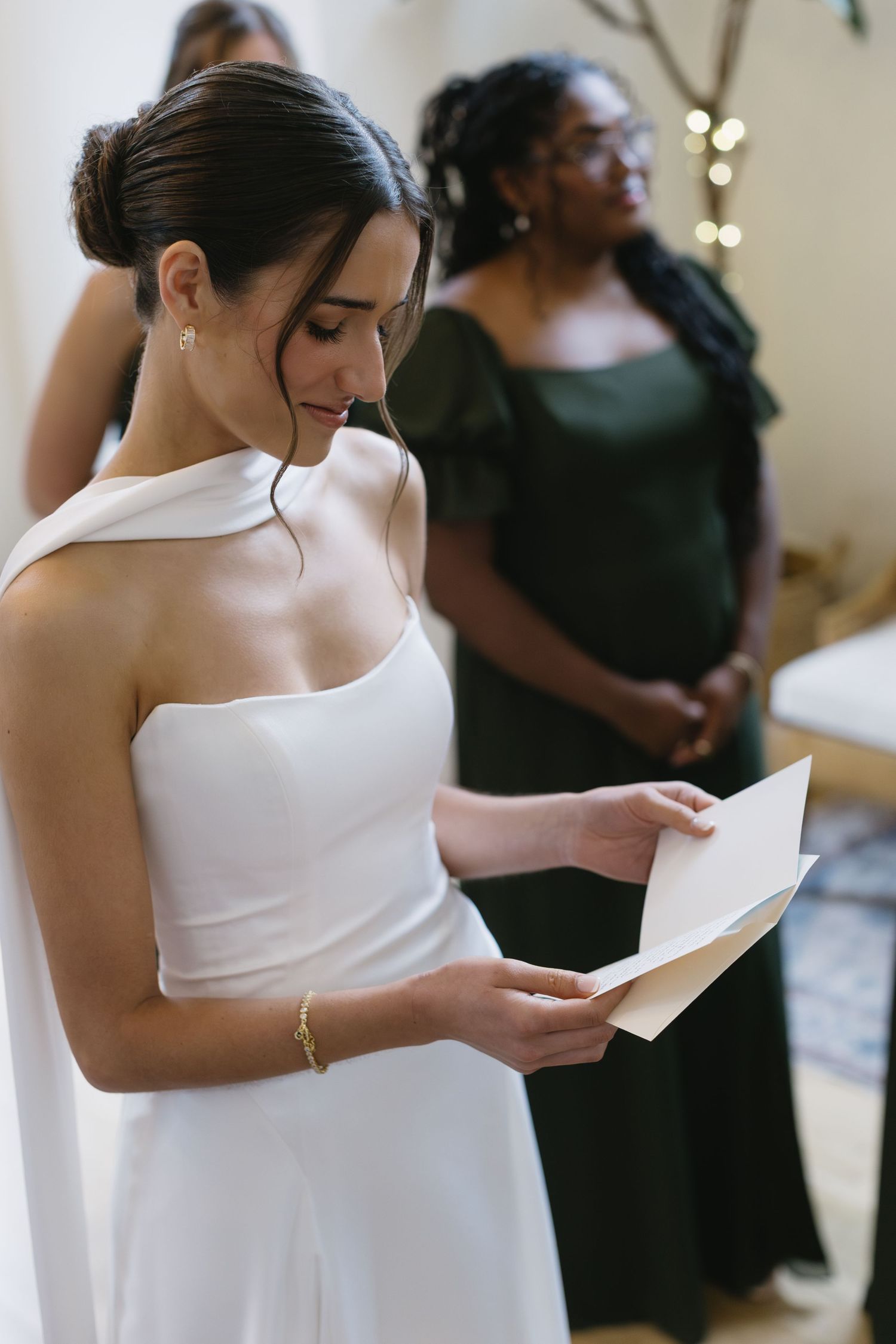Bride in white dress reading a letter during wedding preparations.