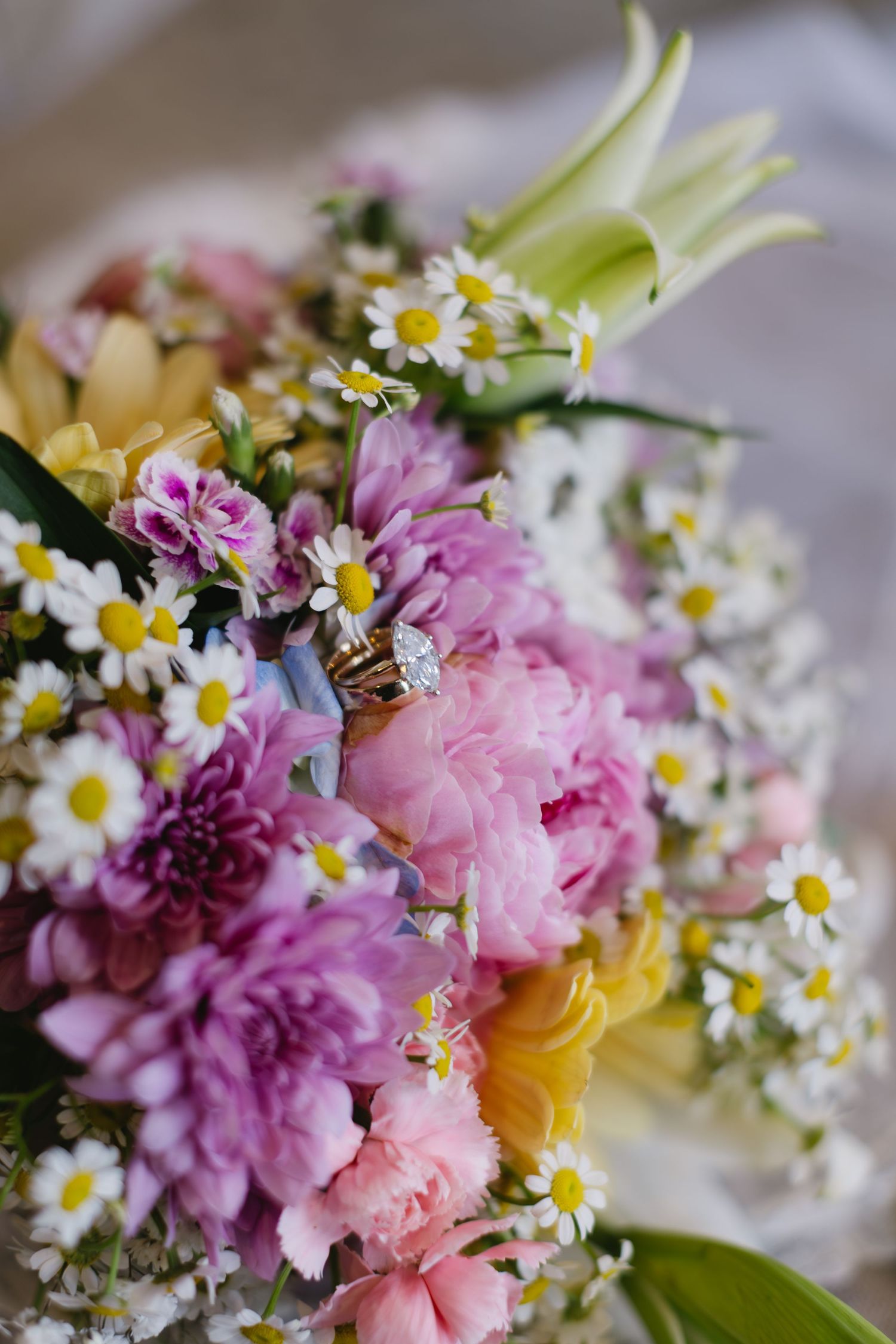 Delicate floral arrangement featuring pink carnations, white daisies, and yellow blooms in soft natural light.