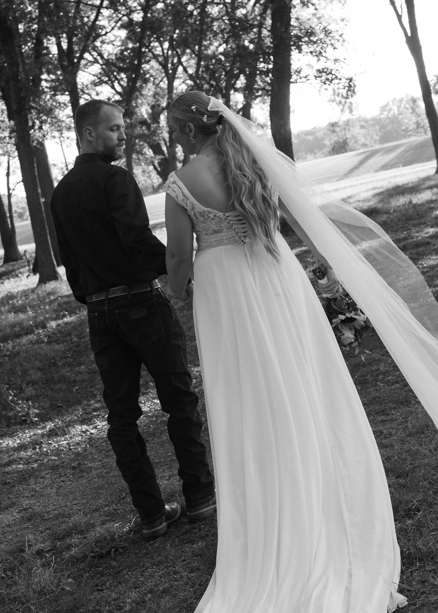 Black and white photo of a bride's flowing dress and veil caught in the wind.