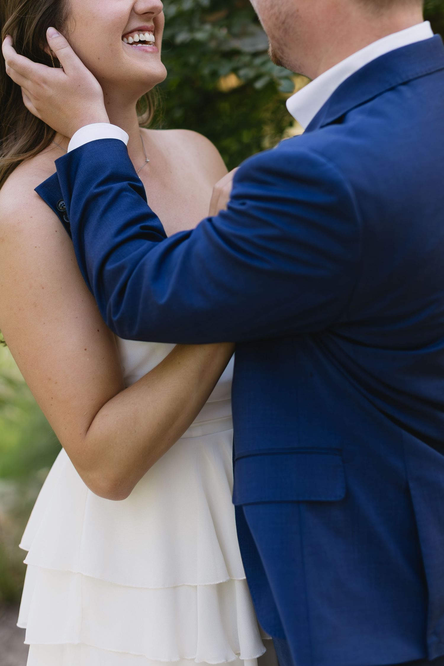 A couple dancing together outdoors with the person in a navy suit twirling their partner in a white dress.