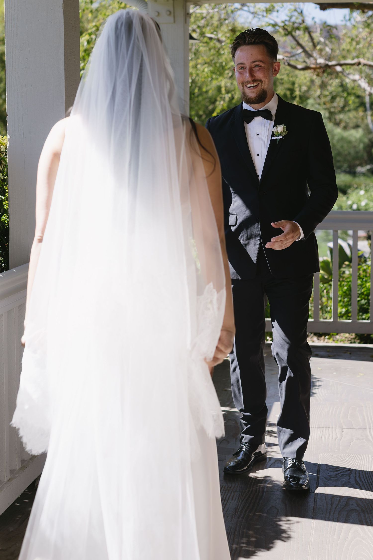 First look wedding moment captured on an outdoor porch with natural lighting.