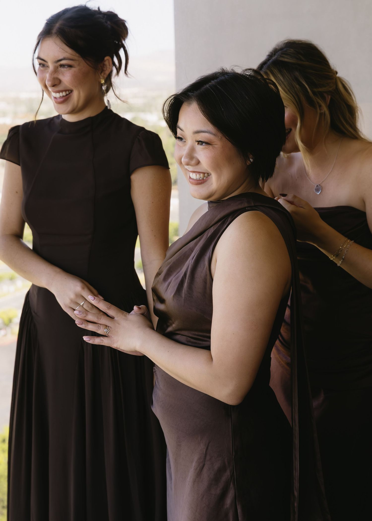 Wedding party members in brown dresses sharing joyful moments together.