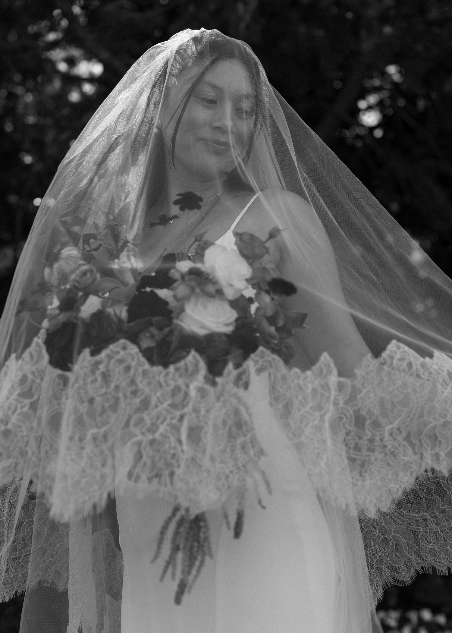 Elegant bridal veil with delicate lace detailing cascades beautifully in black and white photography.