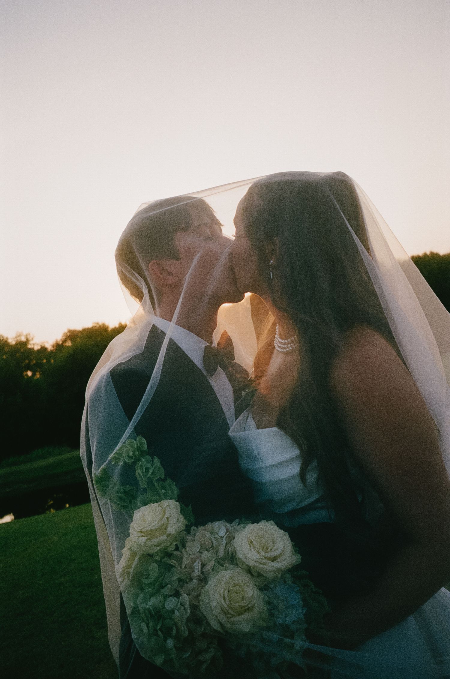 A romantic wedding couple embraces under a veil during sunset in a series of candid shots.