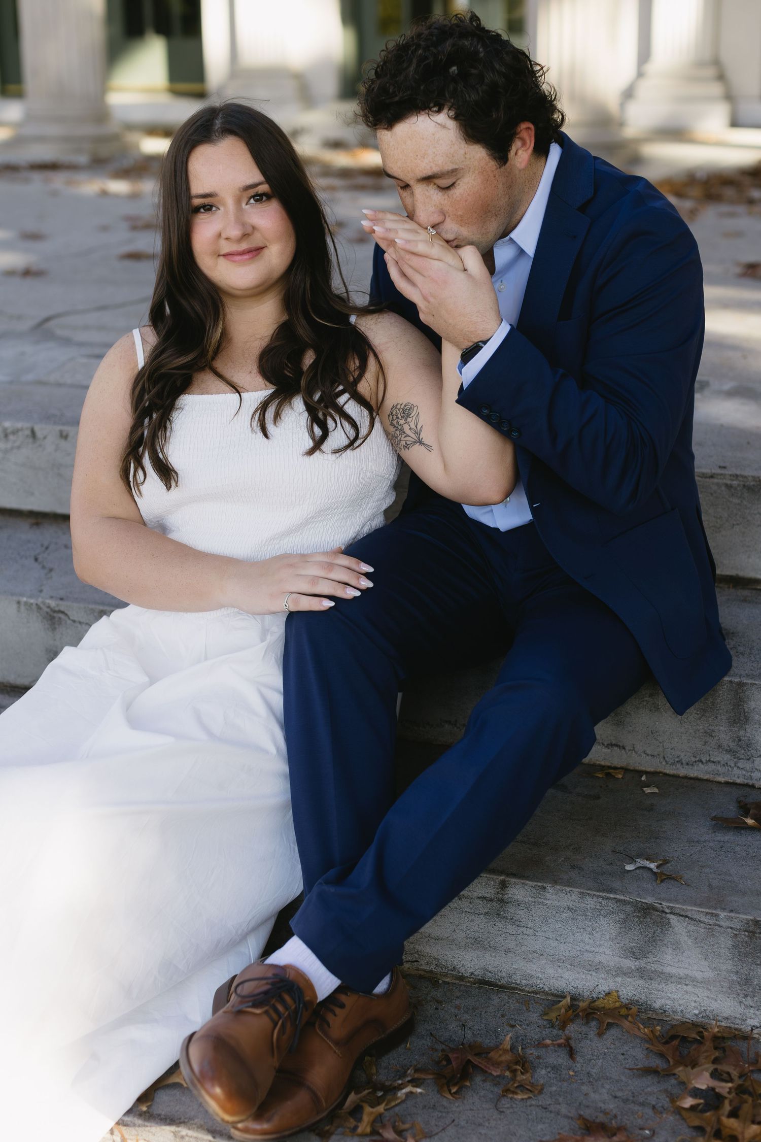 A tender moment between a couple sitting on stone steps outdoors.