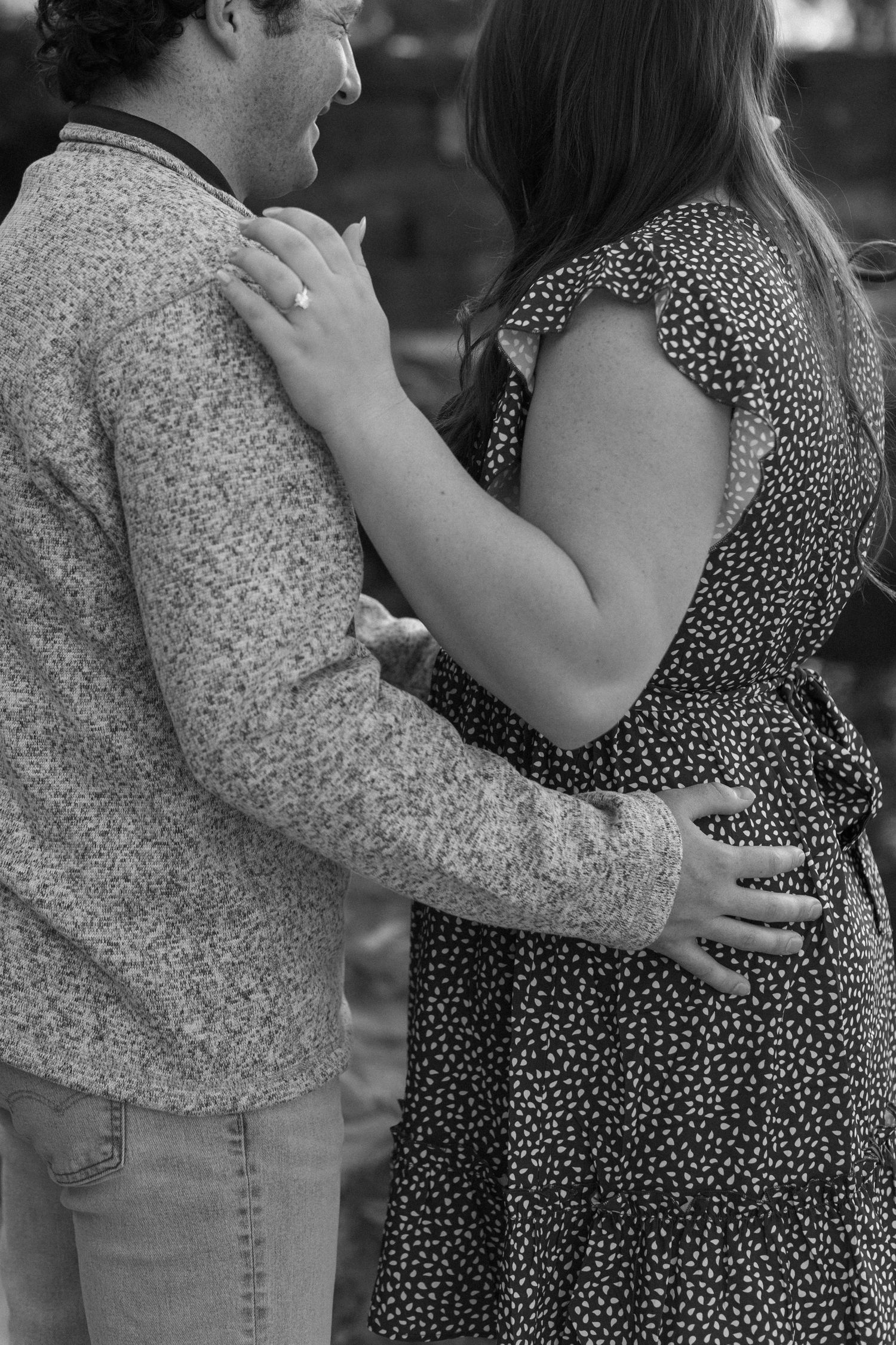 A couple embraces intimately in black and white against a natural backdrop.