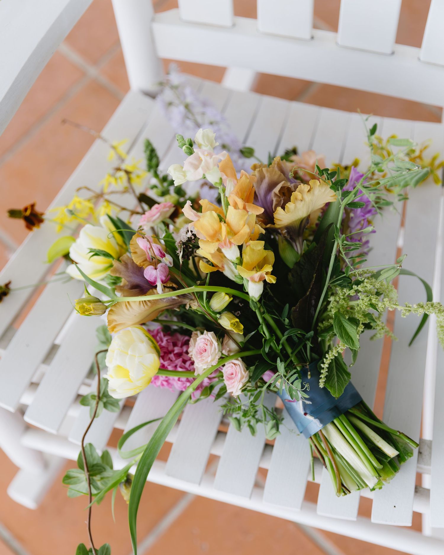 Fresh spring bouquets with yellow and pink flowers laid out on white wooden benches.