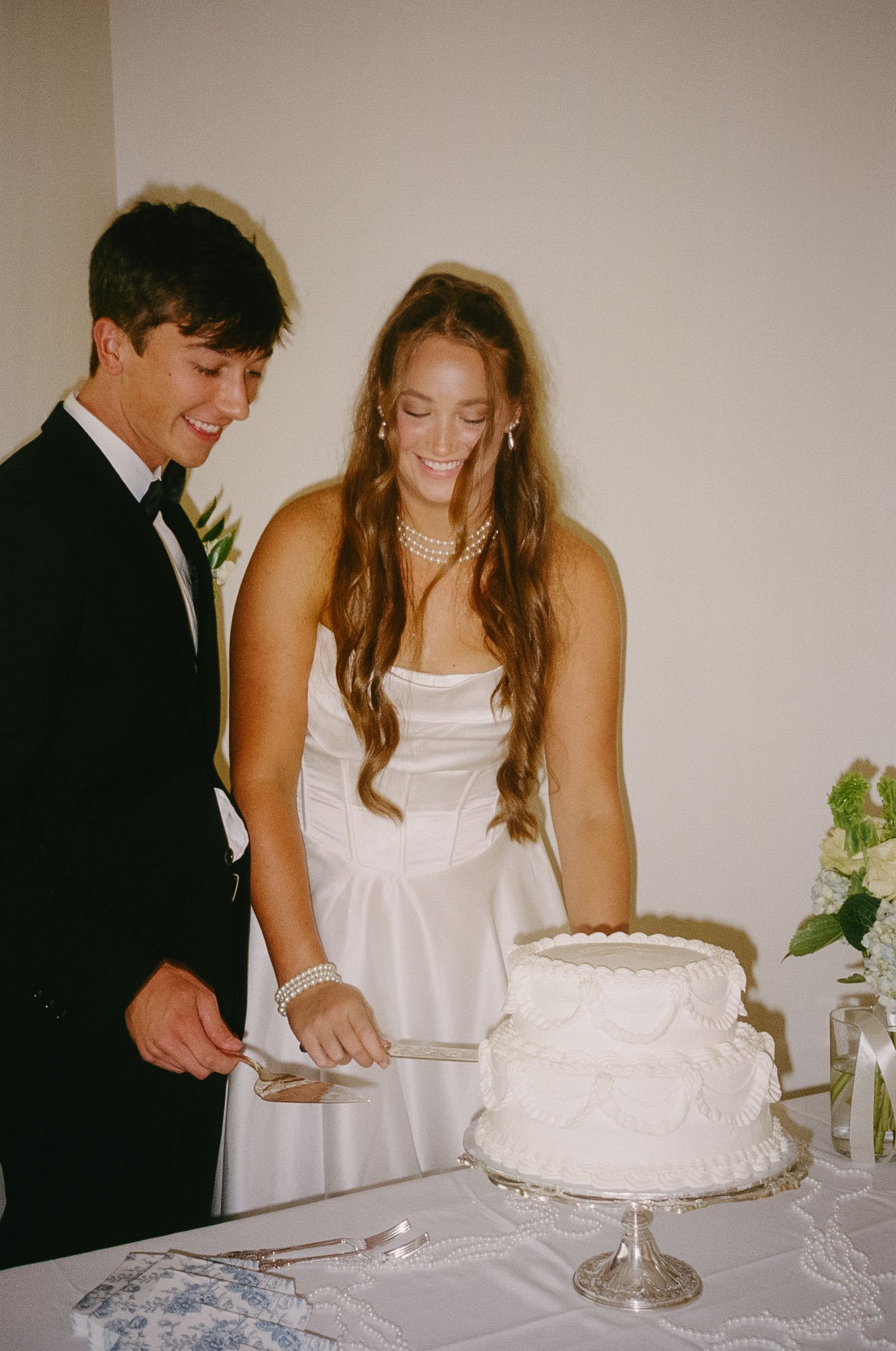 Newlyweds cutting their white wedding cake together at the reception.