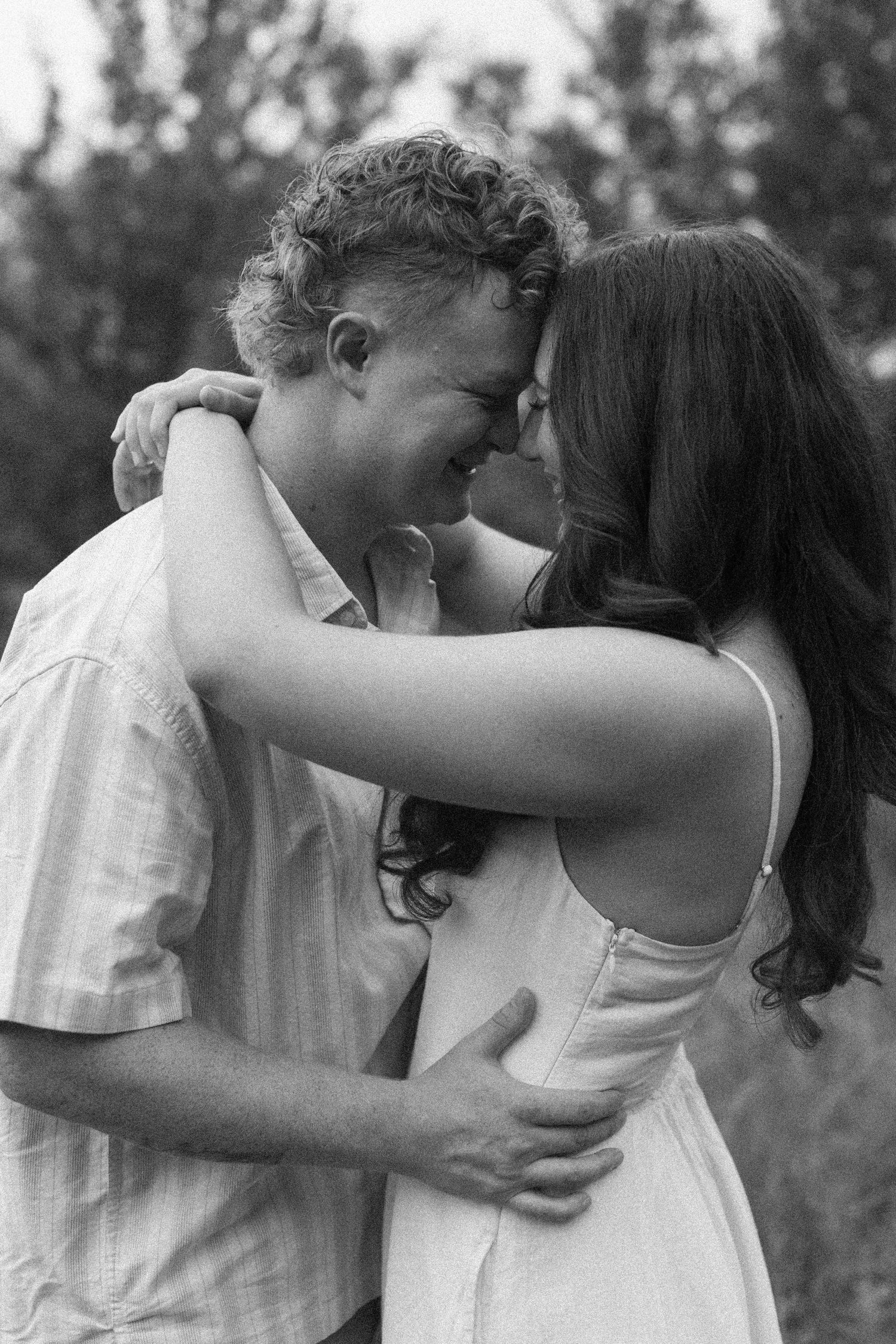 A romantic black and white photo series showing a couple embracing and sharing intimate moments outdoors.