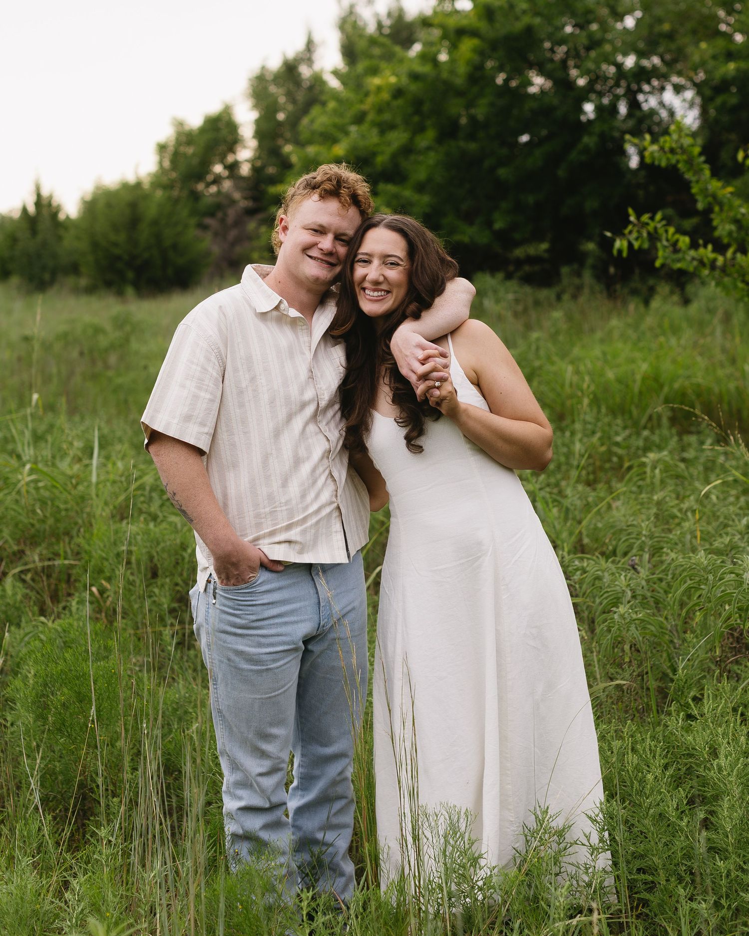 Couple enjoying a romantic moment together in a grassy field on a sunny summer day.