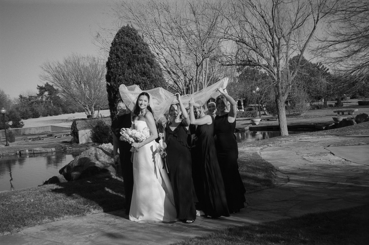 Black and white panorama of outdoor wedding ceremony with winter trees in background.