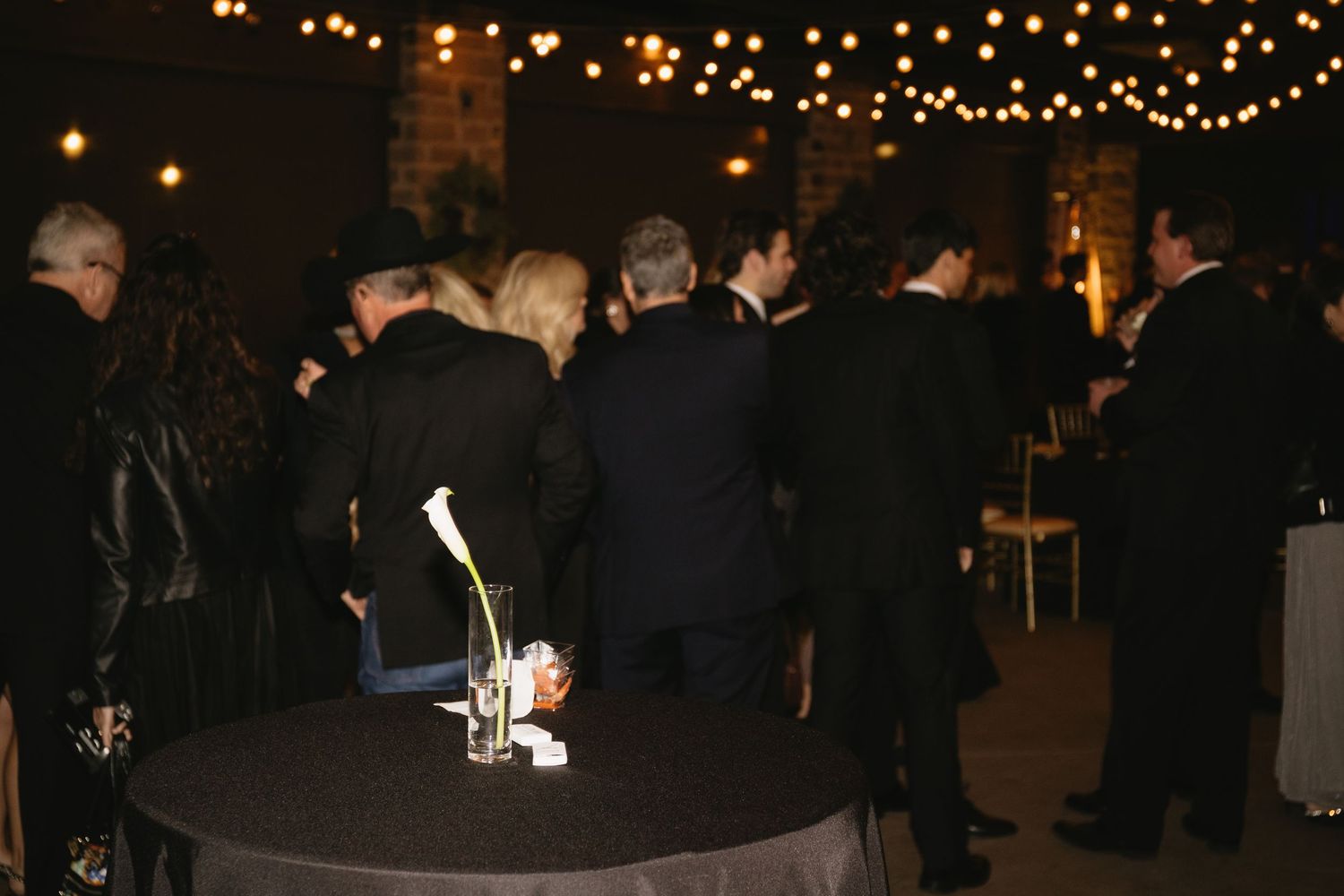 Wedding reception dance floor illuminated by warm string lights overhead.