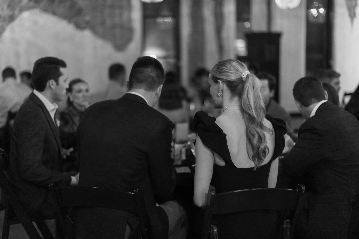 Silhouettes of people seated at tables in a dimly lit venue.
