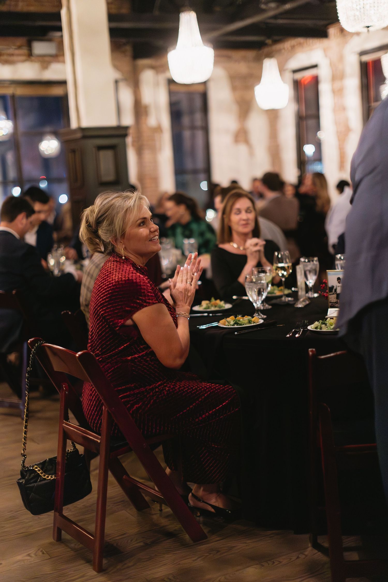 Guest in red dress enjoys dinner at an elegant event with ambient lighting.