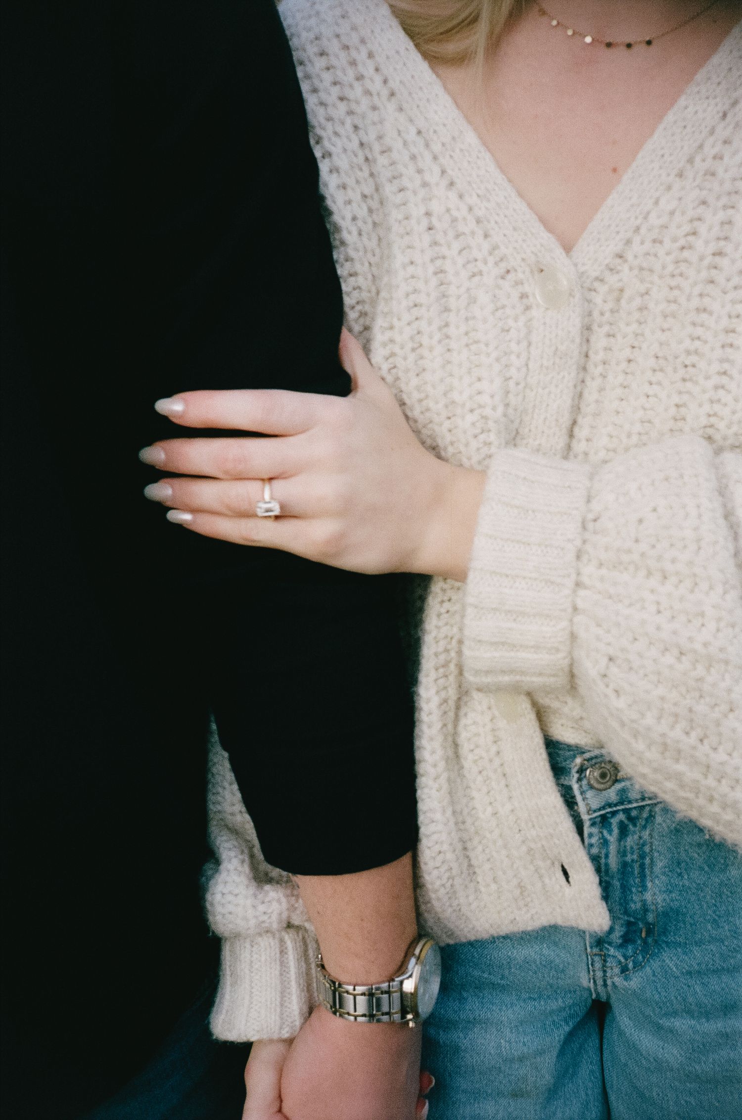 Close-up of hands showing an engagement ring with a cream knit sweater.