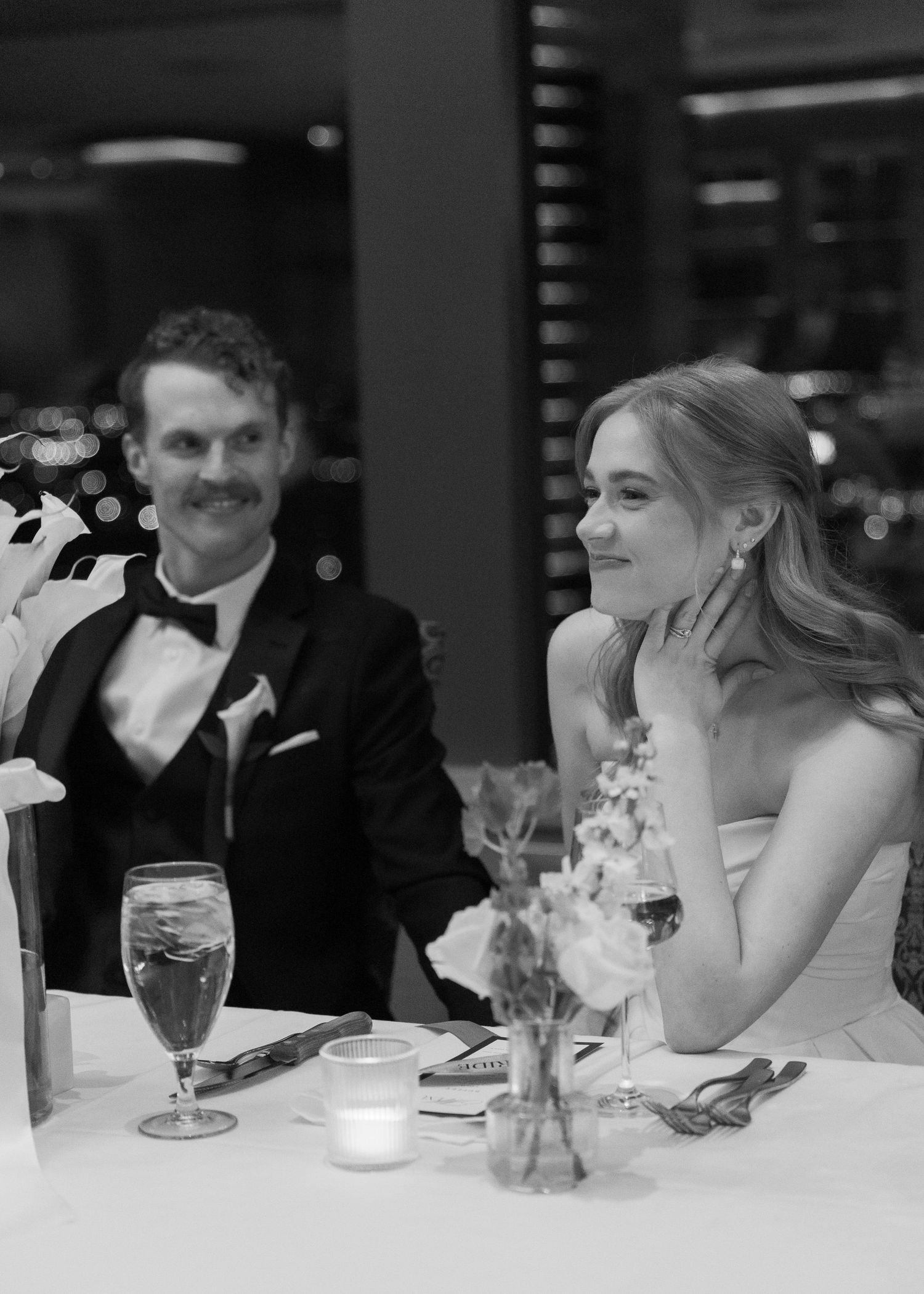 Wedding reception guests seated at tables with candlelit centerpieces.