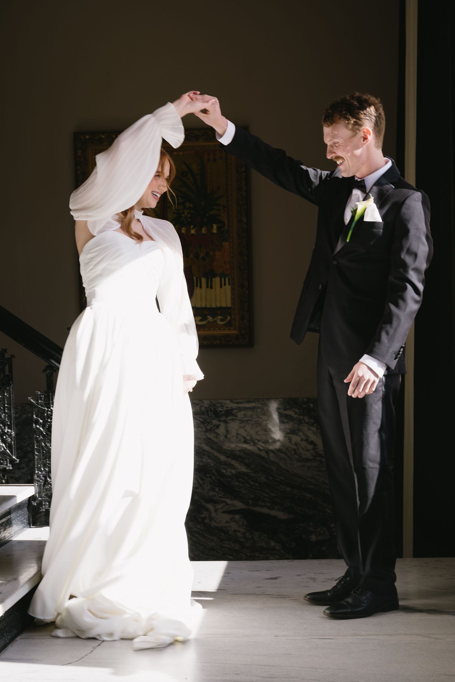Wedding couple dances together in an intimate moment captured in dramatic lighting.