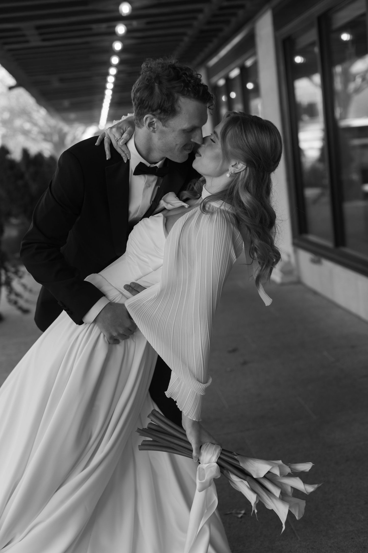 A romantic black and white photo sequence showing a couple sharing a tender kiss under a covered walkway.
