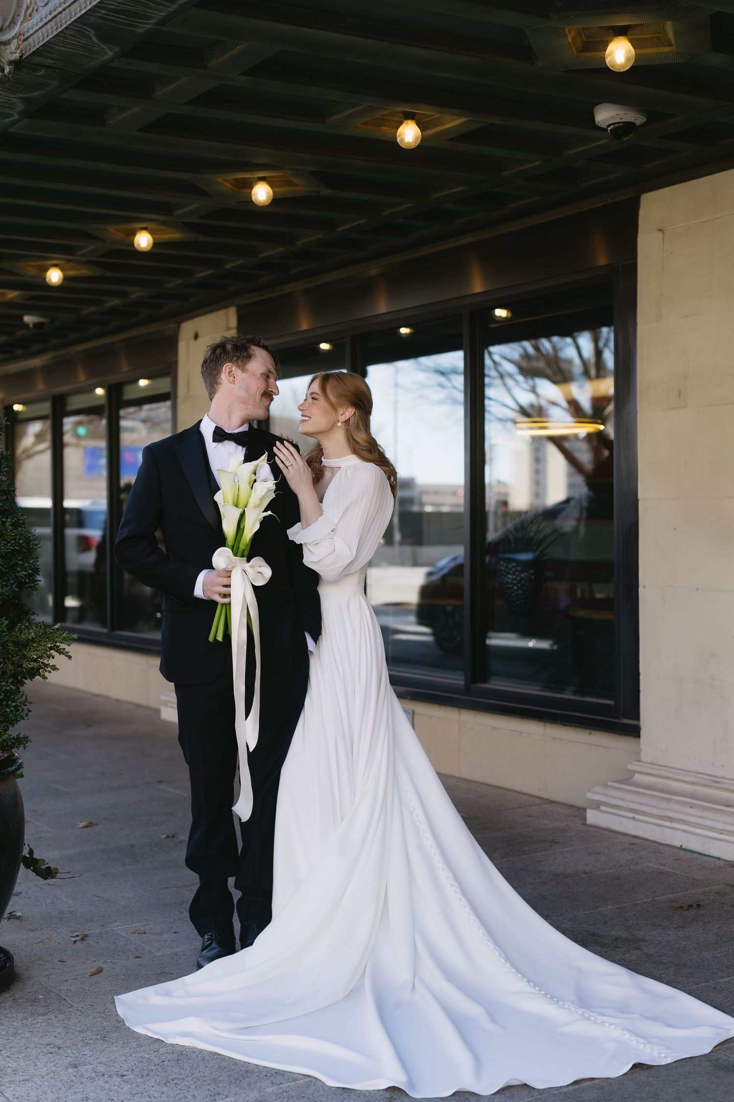 Elegant wedding photos featuring a flowing white dress and black tuxedo against an urban backdrop.