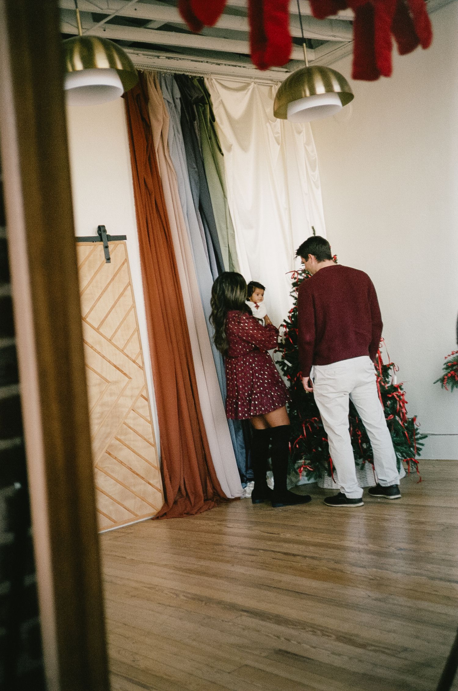 People standing in a hallway with wooden floors and decorative red accents on the walls.