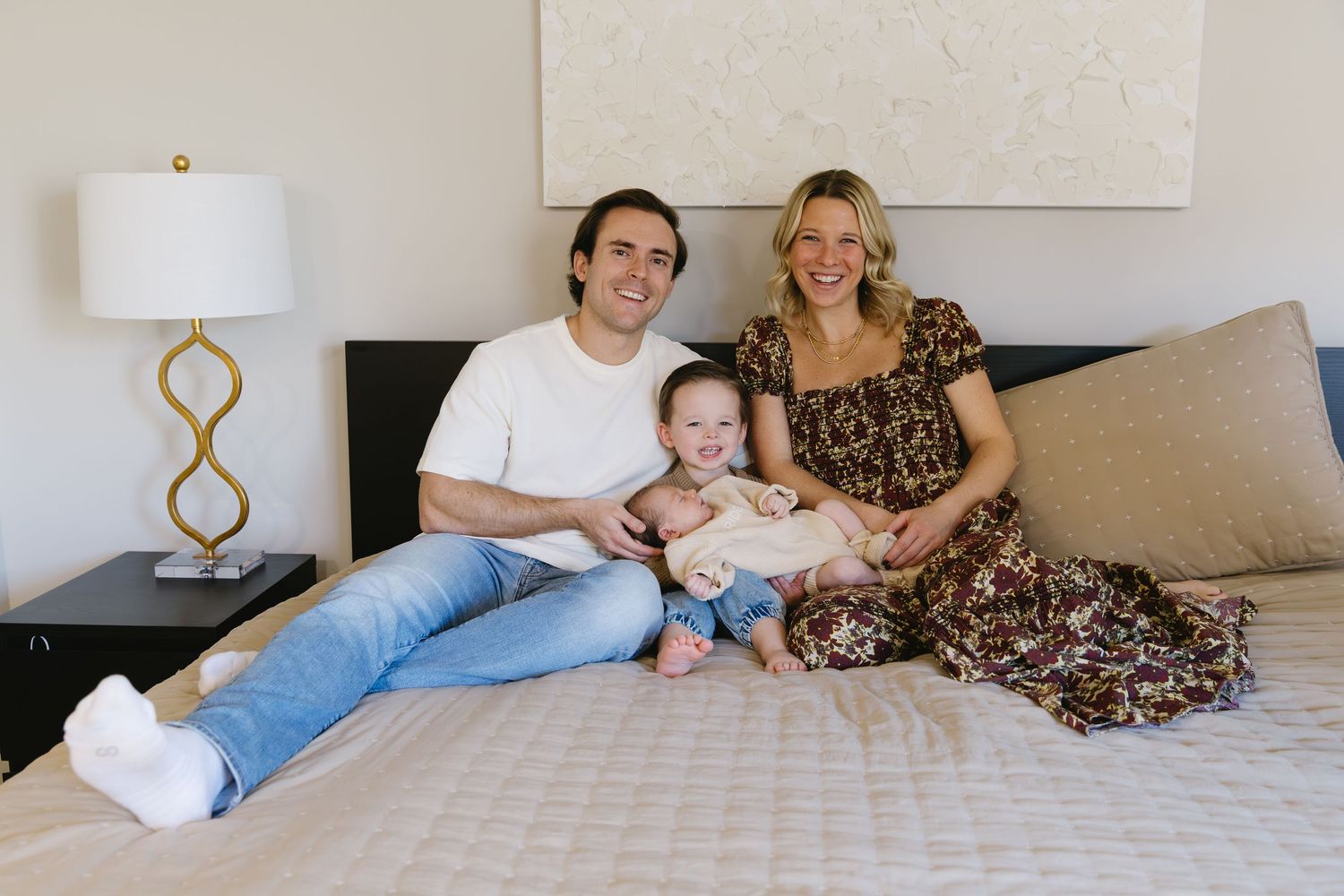 Family relaxing together on a cozy white bed in a modern bedroom.