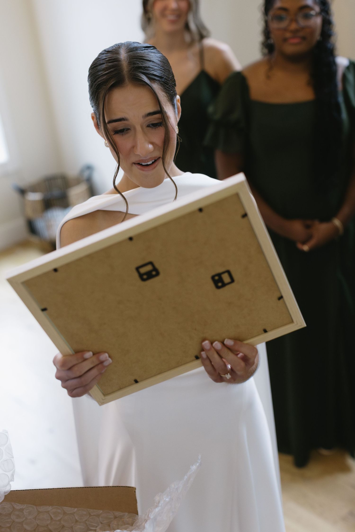 A bride in a white dress reads from a wooden plaque during a wedding ceremony.