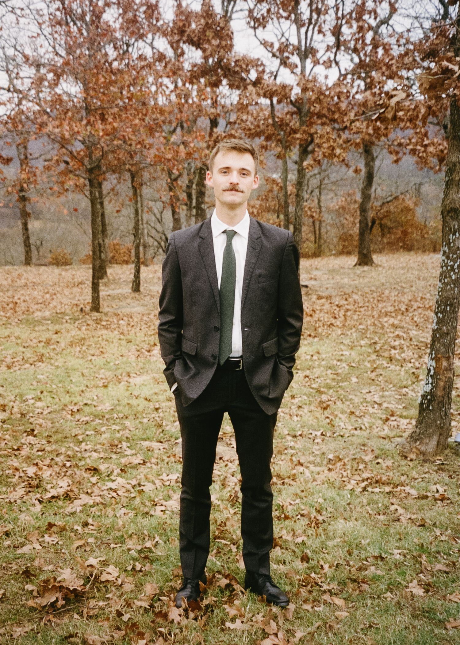 An autumn wedding portrait taken among orange-leaved trees.