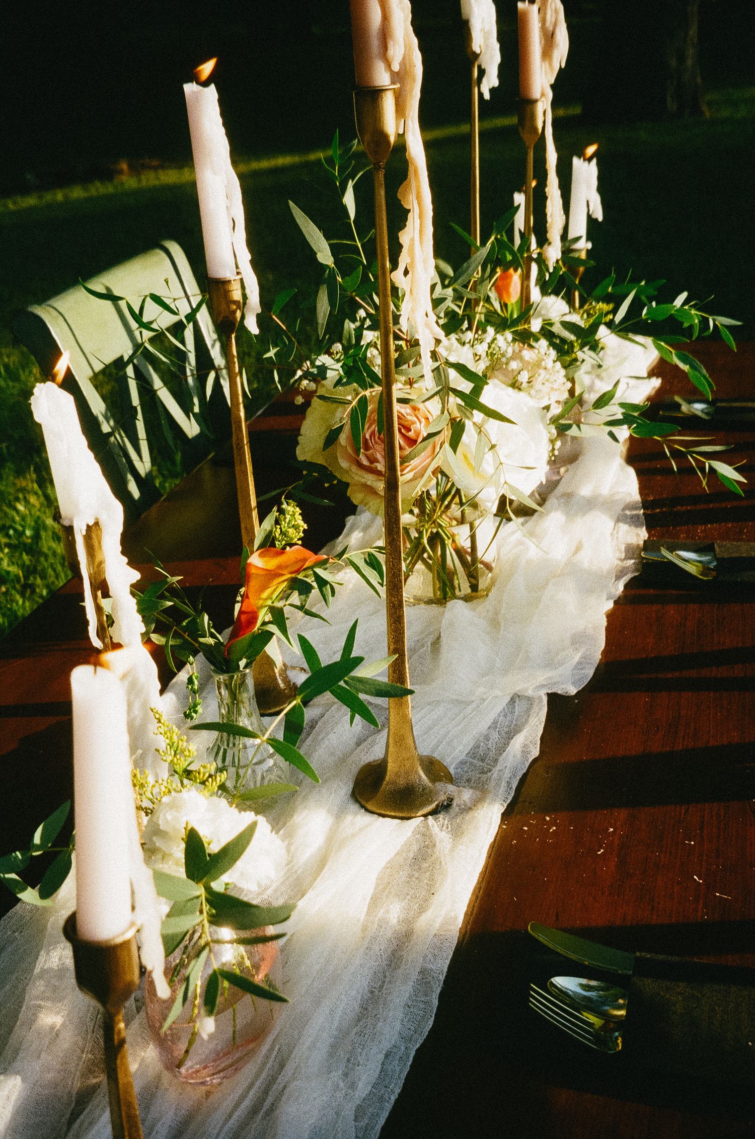 White candles and delicate floral arrangements create an elegant table setting in natural sunlight.